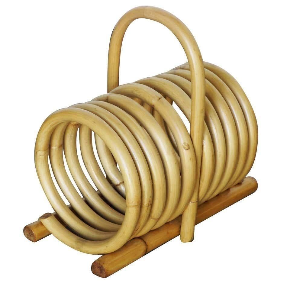 Rattan magazine holder with carrying handle. This Rattan magazine holder features a single-coil steam bent rattan spring for holding up to nine magazines and easy to carry handle. 
Designed in the manner of Paul Frankl. 

Restored to new for you.