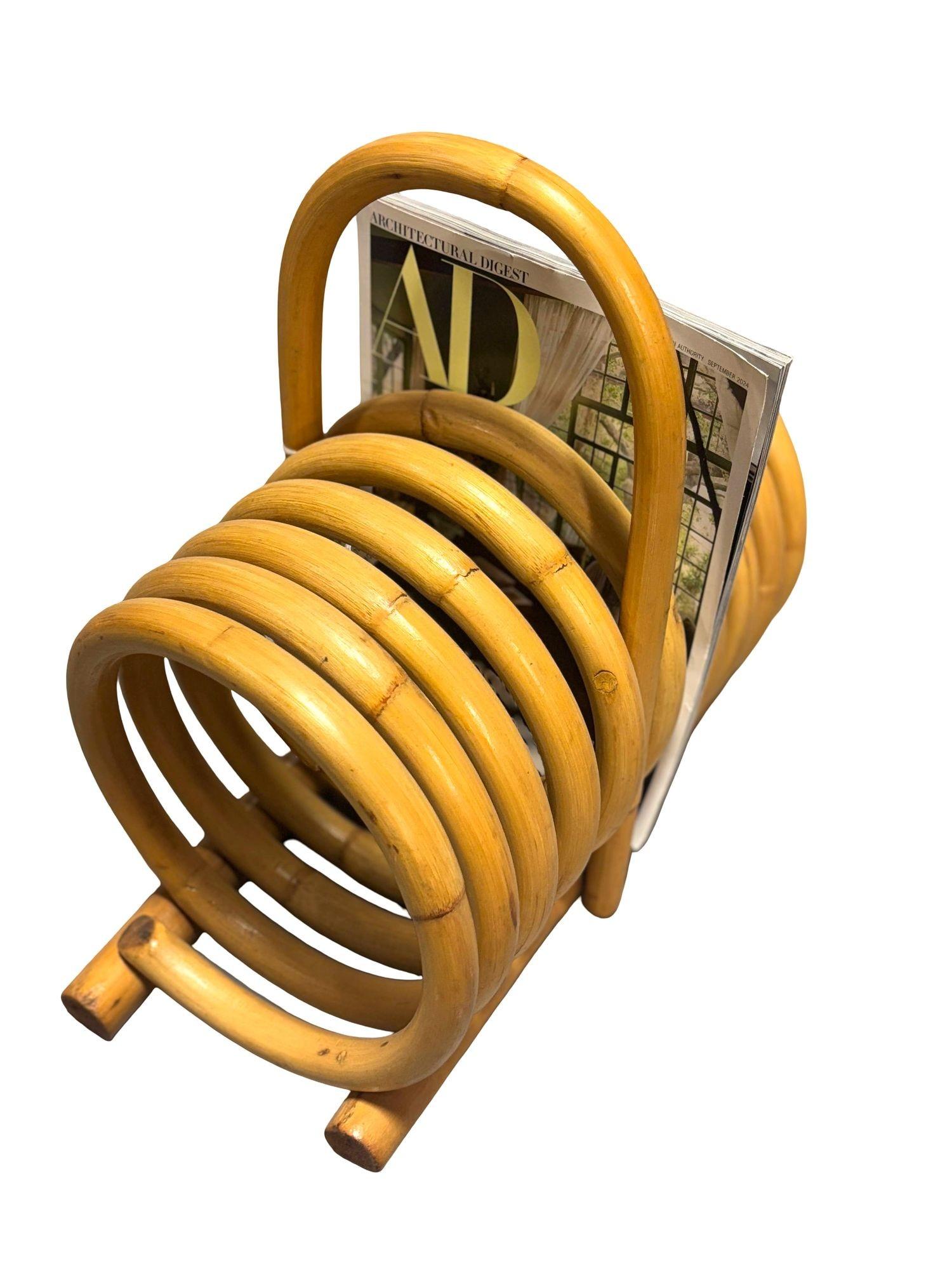 Rattan magazine holder with carrying handle. This Rattan magazine holder features a single-coil steam bent rattan spring for holding up to nine magazines and easy to carry handle. 
Designed in the manner of Paul Frankl. 

Restored to new for you.