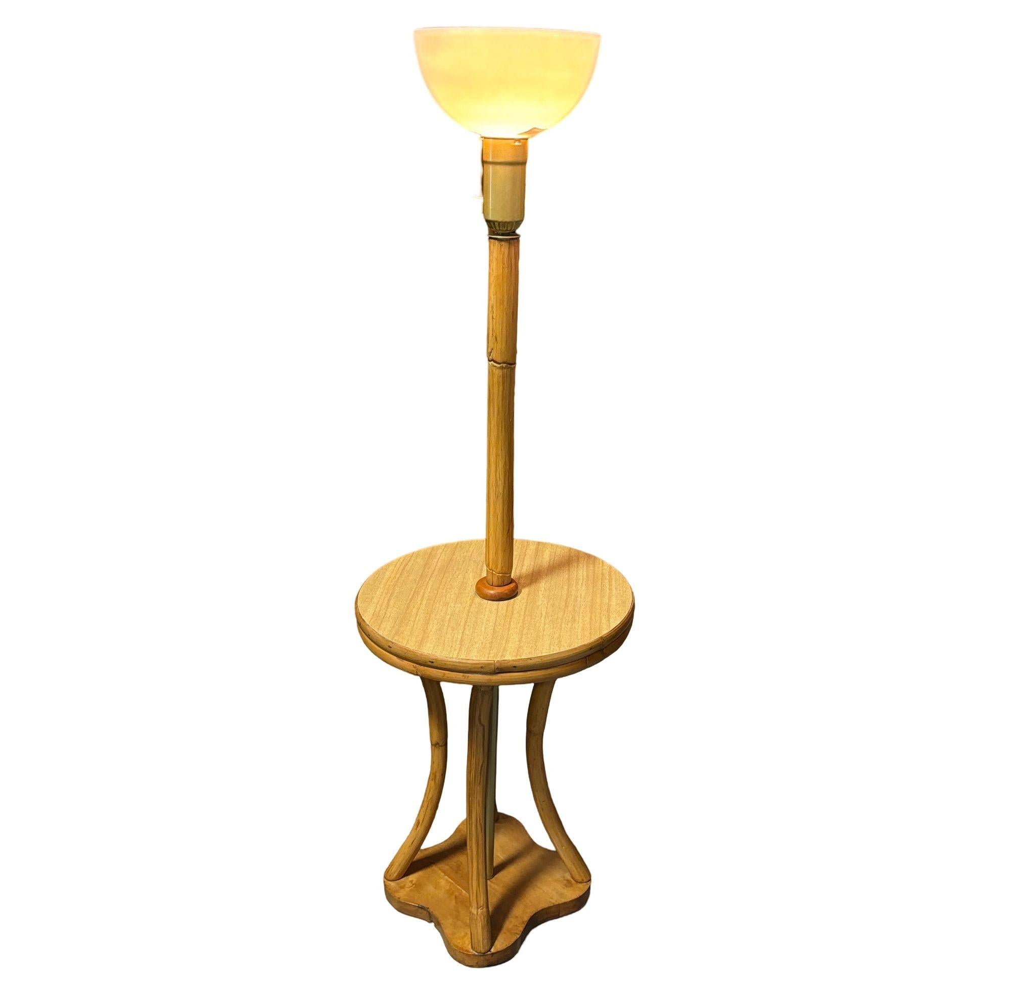 This beautifully restored Paul Frankl-inspired Mid-century rattan & mahogany hourglass-shaped side table floor lamp, is perfect for holding your old fashion nightcap. The table features 4 rattan poles branching from a solid mahogany base connected
