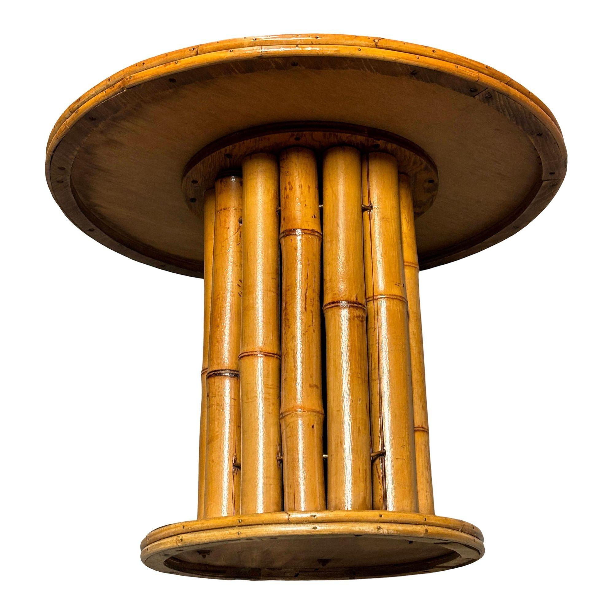 This restored rattan round pedestal end table boasts a charming vertically stacked rattan design featuring vertically stacked rattan poles sandwiched between a mahogany top and mahogany base. Its natural texture and timeless appeal make it a