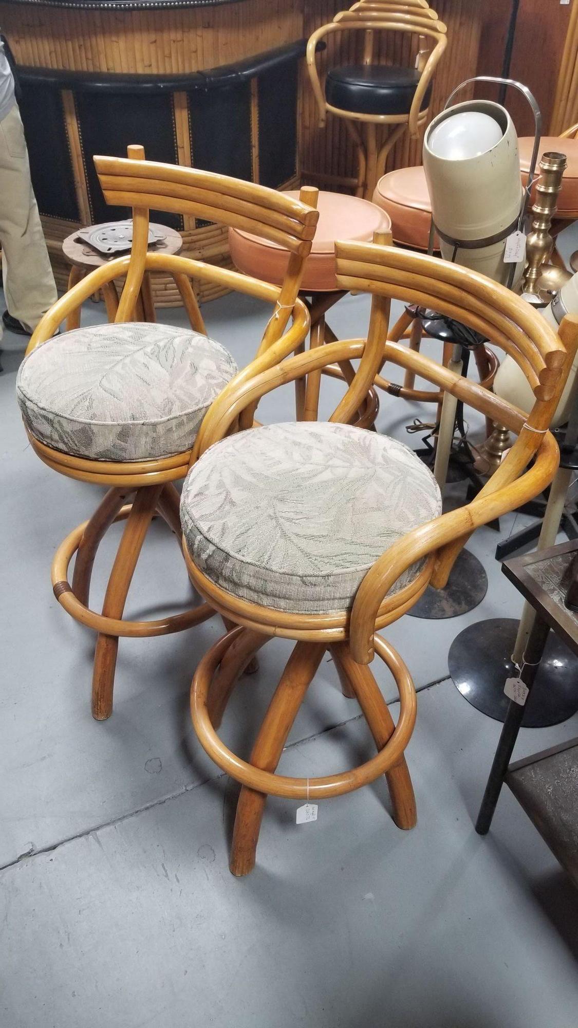 Restored rattan stacked-back pair of two barstools with neutral taupe-green colored botanical leaf fabric swivel seats.

Elevate your seating experience with these meticulously restored rattan bar stools. Featuring swivel fabric seats and a stacked