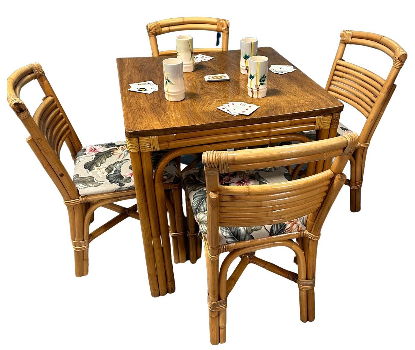 Restored rattan dining set featuring a square rattan table with beautiful side wrappings and five-strand legs and a set of four stacked strand rattan chairs.

Restored Mid-Century era four-person rattan dining table with five pole rattan legs and a