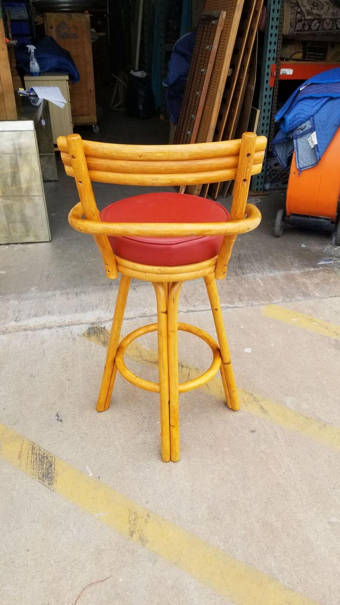 Restored rattan stacked-back set of 4 barstools in red Naugahyde swivel seats.

Elevate your seating experience with these meticulously restored rattan bar stools. Featuring swivel fabric seats and a stacked backrest for comfort and style, these