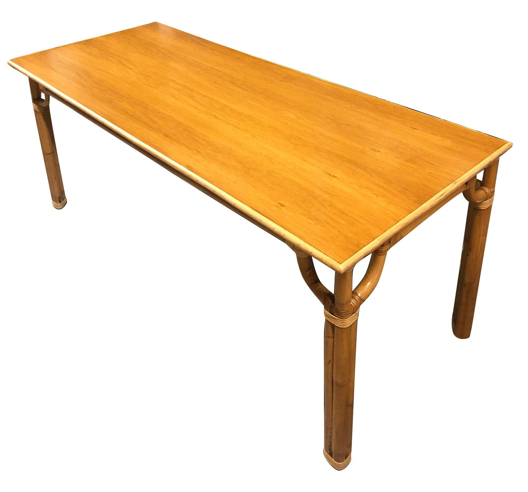 This beautifully restored Paul Frankl-inspired Mid-century rattan three-strand long dining table. Crafted with a large Mahogany wood top held up with triple pole rattan legs and corners finished in wicker wrappings, this piece combines Mid-century
