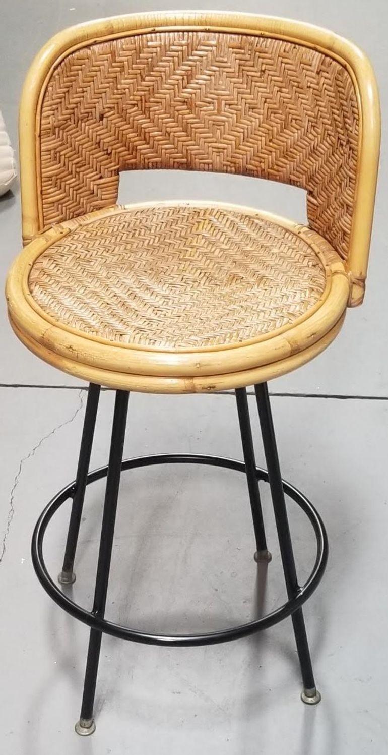 Rattan and wicker bar stool with swivel iron bases by Seng of Chicago. This chair features a wicker seat and back and rests in a rattan frame mounted to an iron swivel base.  This delicate combination of rattan and metal is a perfect match for any