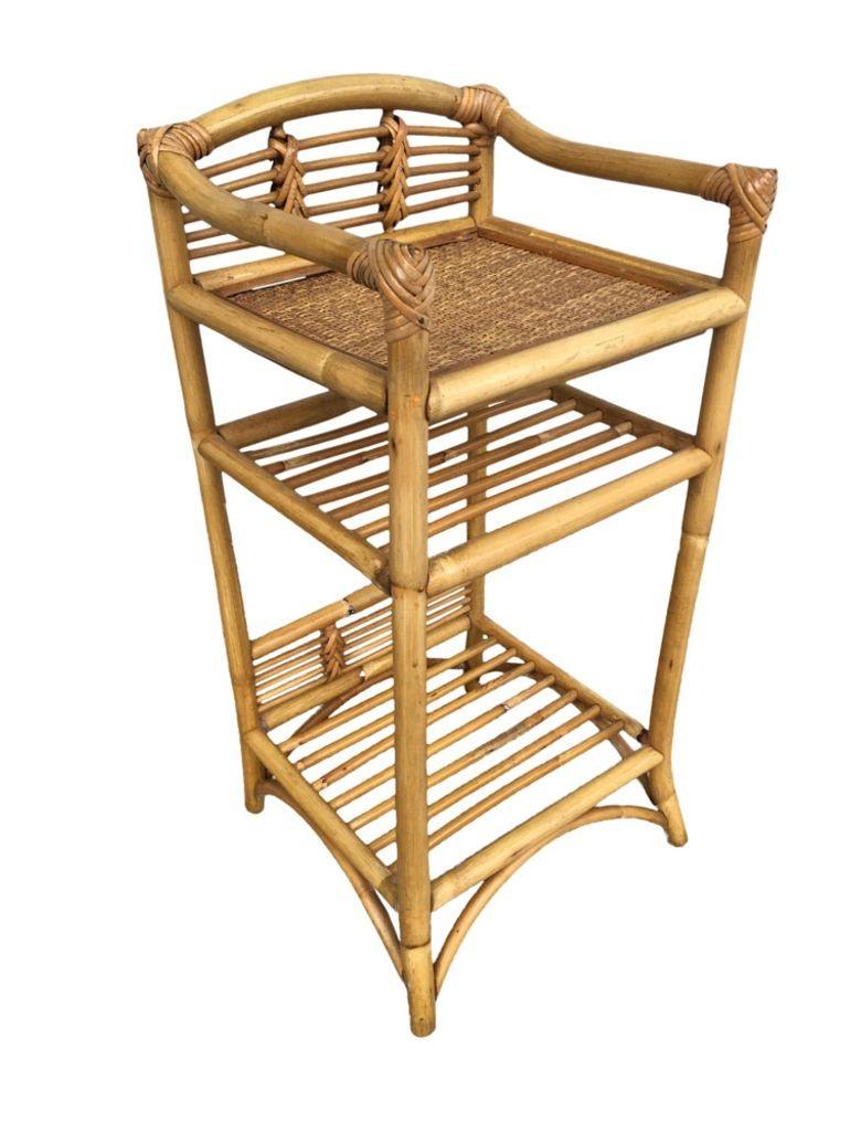 Vintage three-level rattan book self with hand-woven rice mat shelf on top and decorative stick rattan backplate along the top and bottom to display a decorative object such as a vase or statue. 
1950, United States
We only purchase and sell only