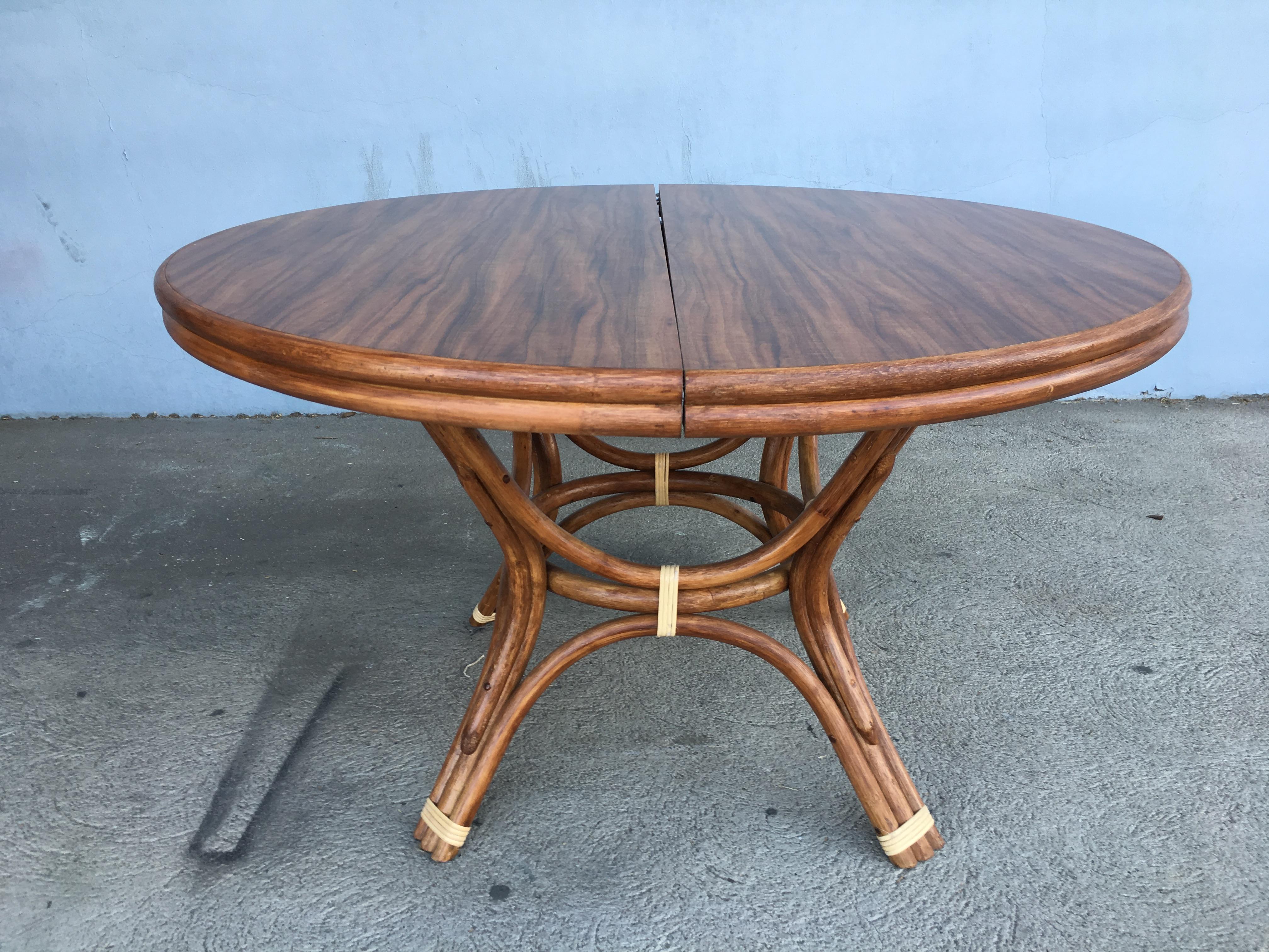 Restored round rattan dining table with original Formica top complete with two leaves for easy expansion from a 4 to 8 person table setting. Restored to new for you. All rattan, bamboo and wicker furniture has been painstakingly refurbished to the