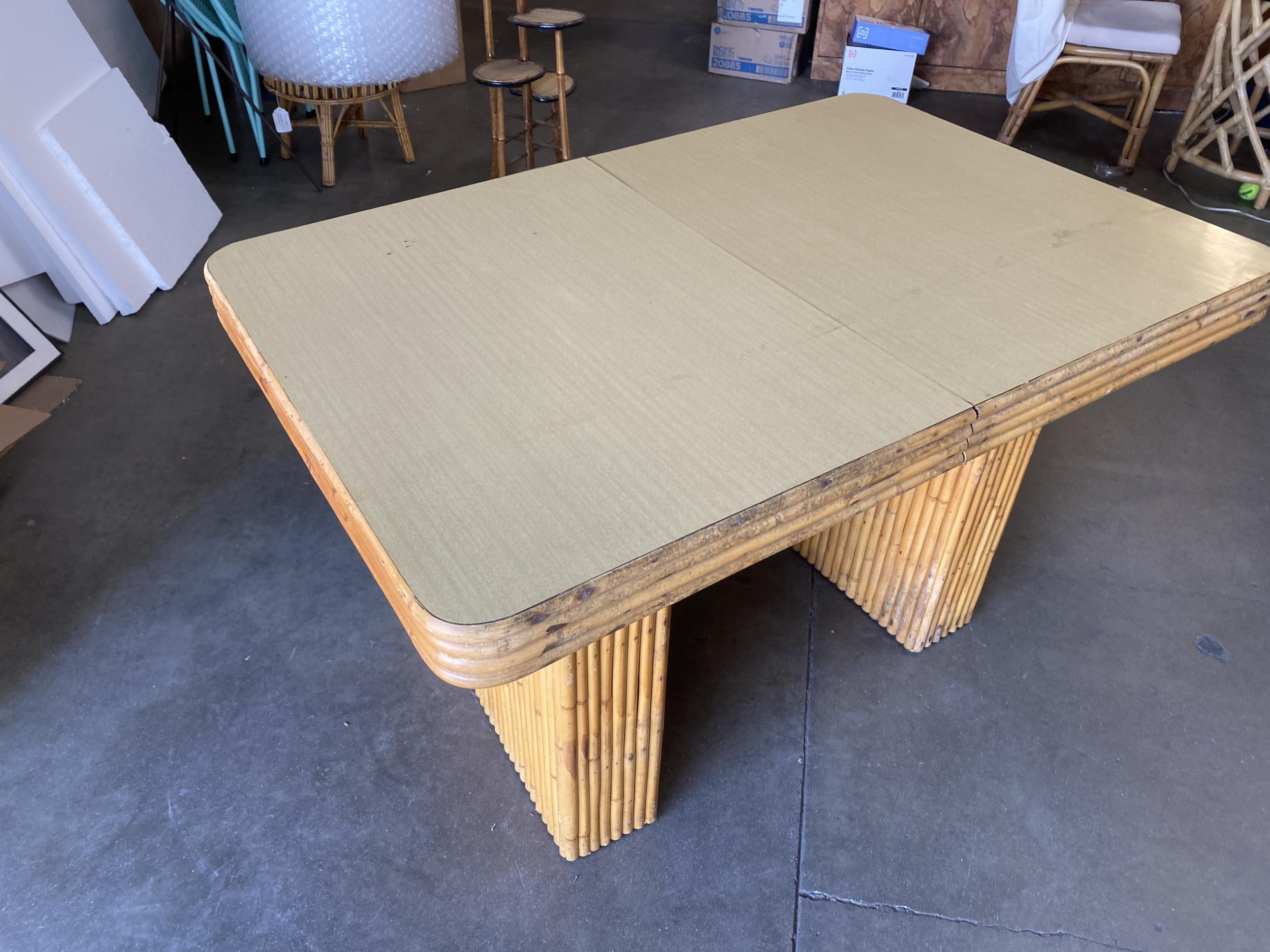 Midcentury six-person rattan dining table with vertically stacked rattan base legs, horizontal stacked rattan trim, and blond Formica mahogany table.

Measures: Table: 29.5
