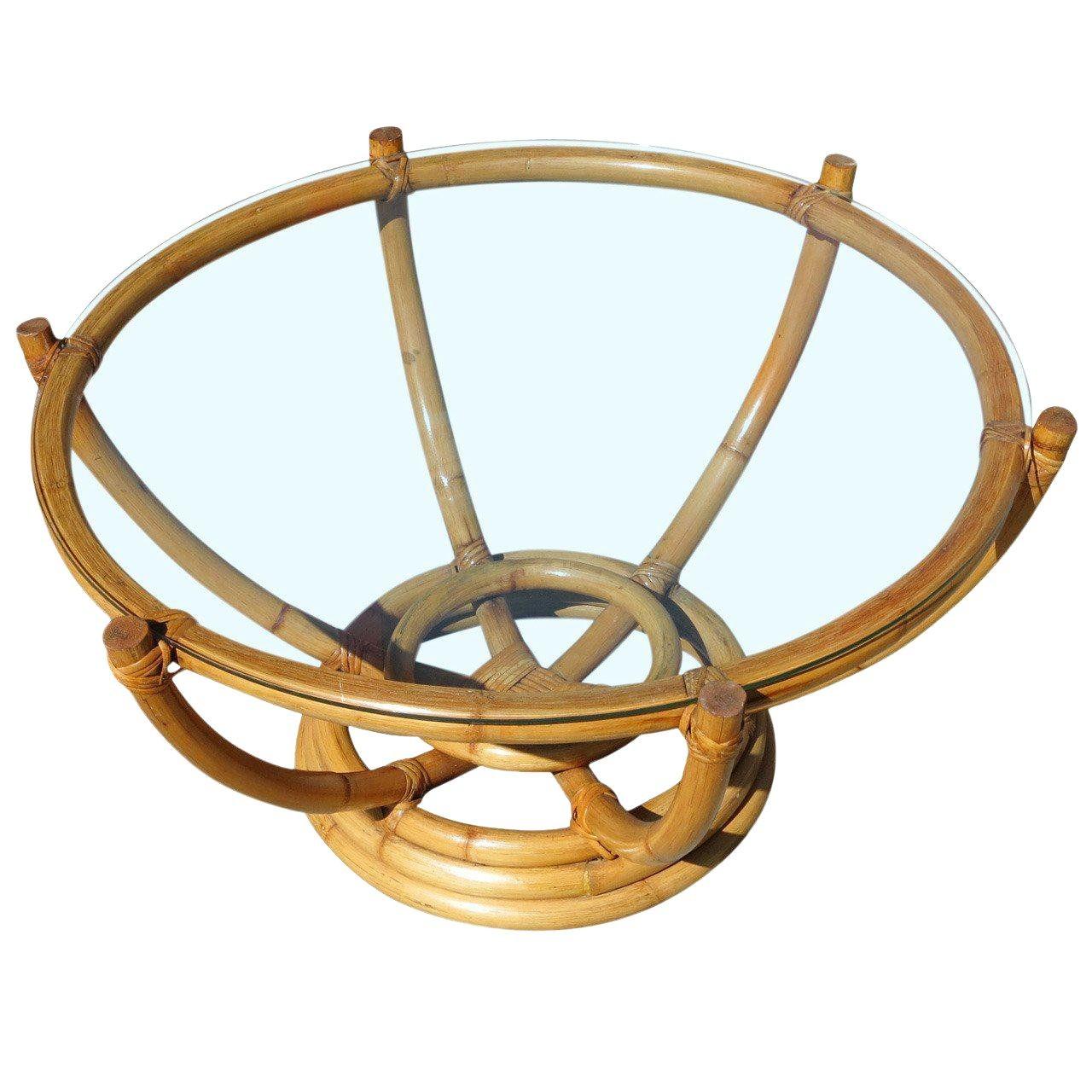 Circa 1940 Mid-century six-pole rattan coffee table with stacked rattan round base. The six rattan poles organically branch outward to a circular top made of a single piece of bent rattan. The glass top rests atop the poles, exuding an almost