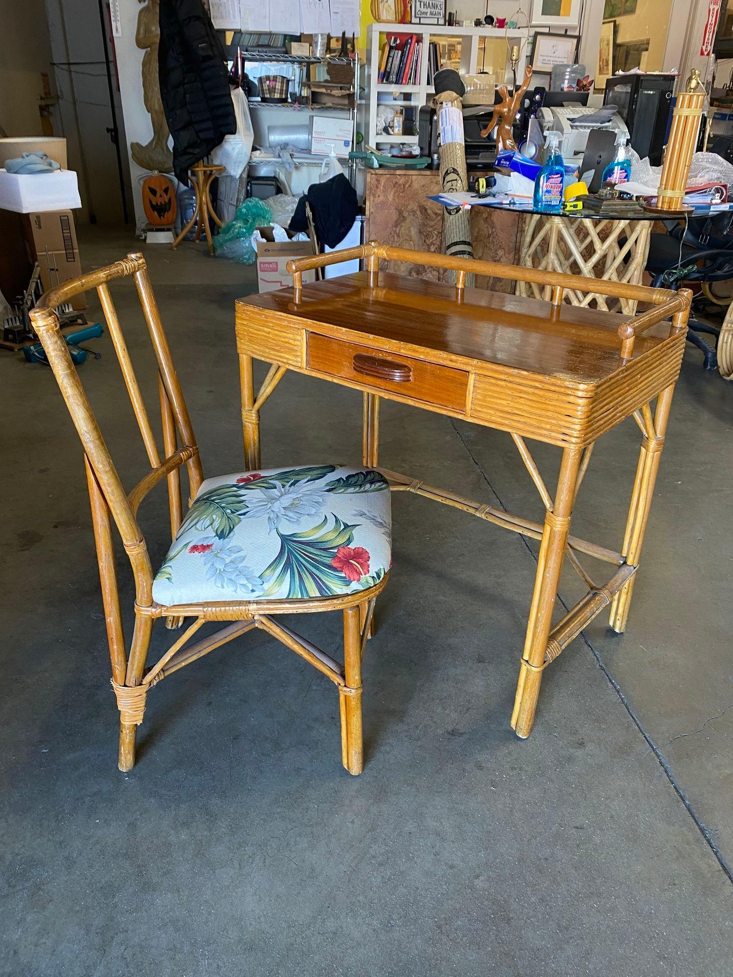 Original Mid Century Mahogany and rattan secretary desk with matching chair. This late 1950s desk features a mahogany top with rattan legs and wicker sides, a center drawer, and built-in top holders.

Desk: H 34 in. x W 16 in. x D 186 in.
Chair: H