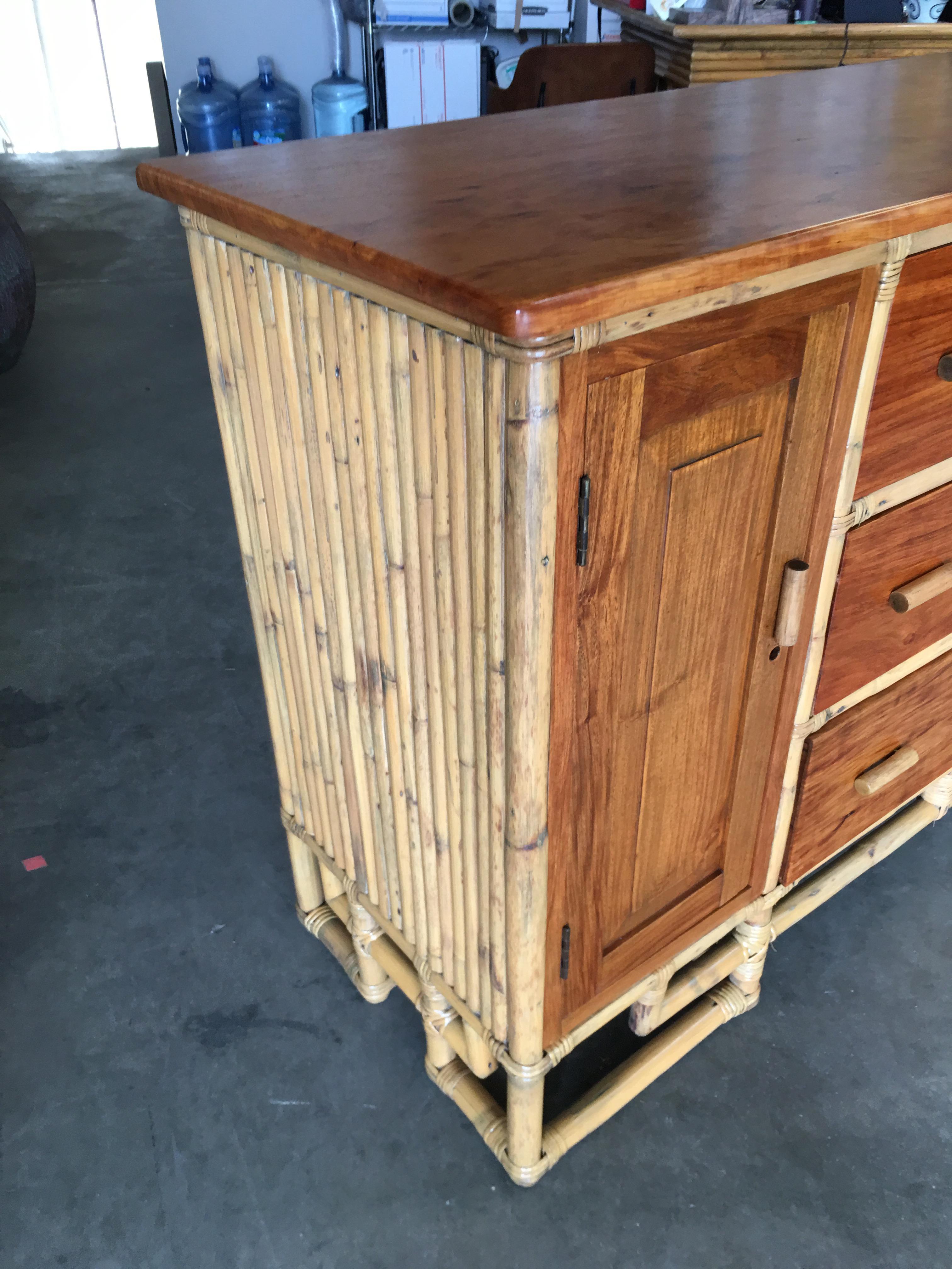 Paul Frank designed Vertically stacked rattan sideboard with a mahogany top resting on an Asian inspired base. It contains three pull-out drawers and two side cabinets with a fixed shelf in each. Restored to new for you. All rattan, bamboo and