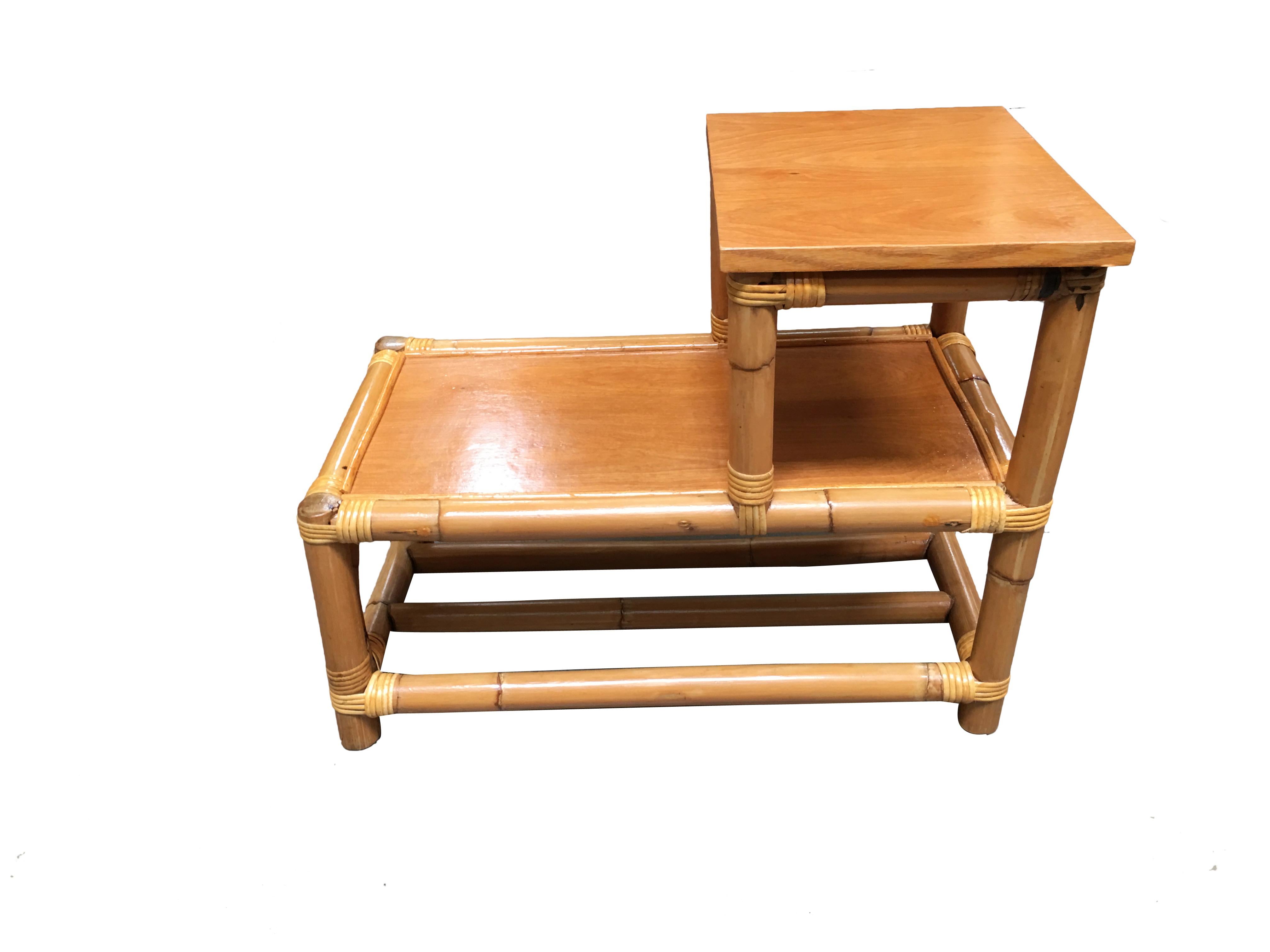 Stick leg rattan side table with two-tier wood tops, circa 1950. Designed in the manner of Paul Frankl. 
We only purchase and sell only the best and finest rattan furniture made by the best and most well-known American designers and manufacturers