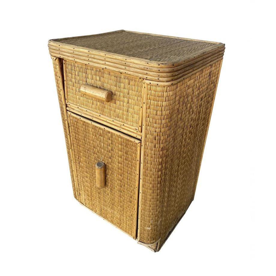 Streamline stick rattan side table nightstand with grass-mat coverings, edges are finished with brass nails. The side table has a pull-out drawer and cabinet underneath.
1930, United States
We only purchase and sell only the best and finest rattan