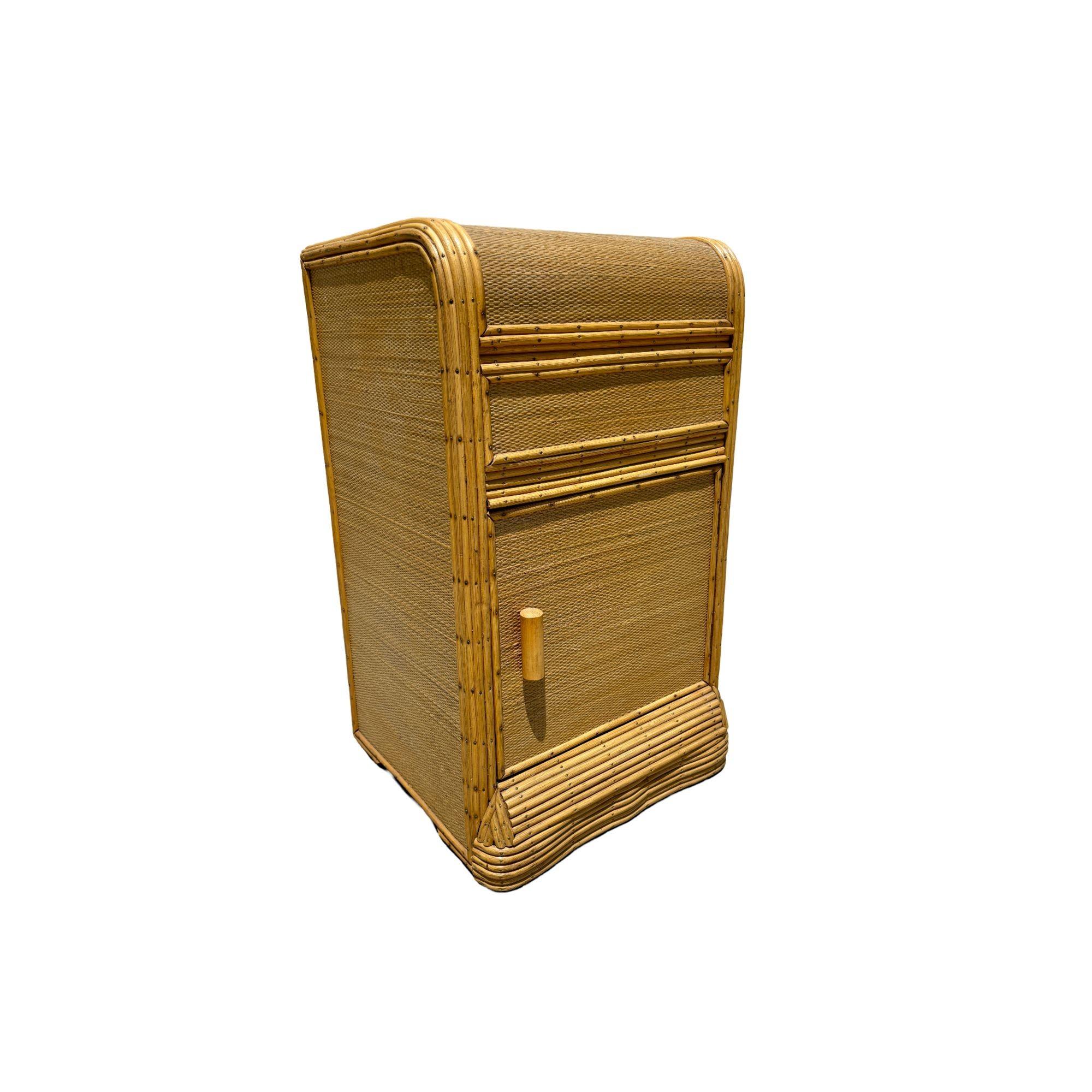Table d'appoint en rotin à bâtons de l'époque Art déco, avec un revêtement en tapis de gazon et des bords finis avec des clous en laiton. La table d'appoint est dotée d'une porte unique qui s'ouvre par l'avant et d'un tiroir central.

Conçu à la