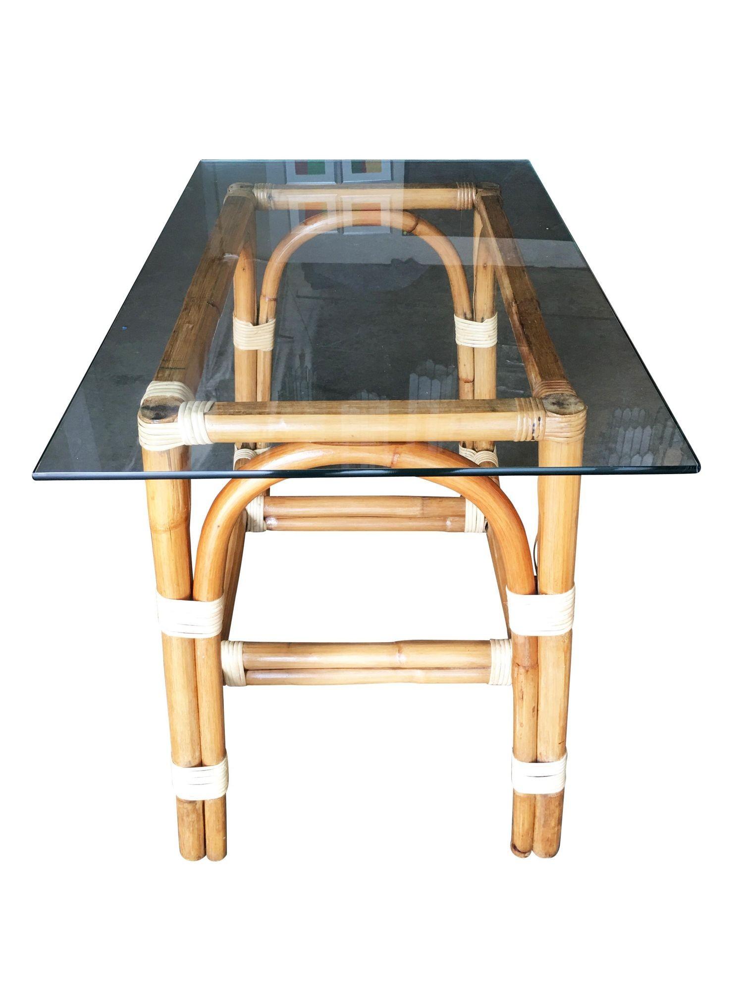 This beautifully restored Paul Frankl-inspired rattan blends vintage charm with modern comfort. Restored rattan side table with a glass top. The table features wicker-wrapped accents with unique bent-pressed legs. All meticulously refinished to