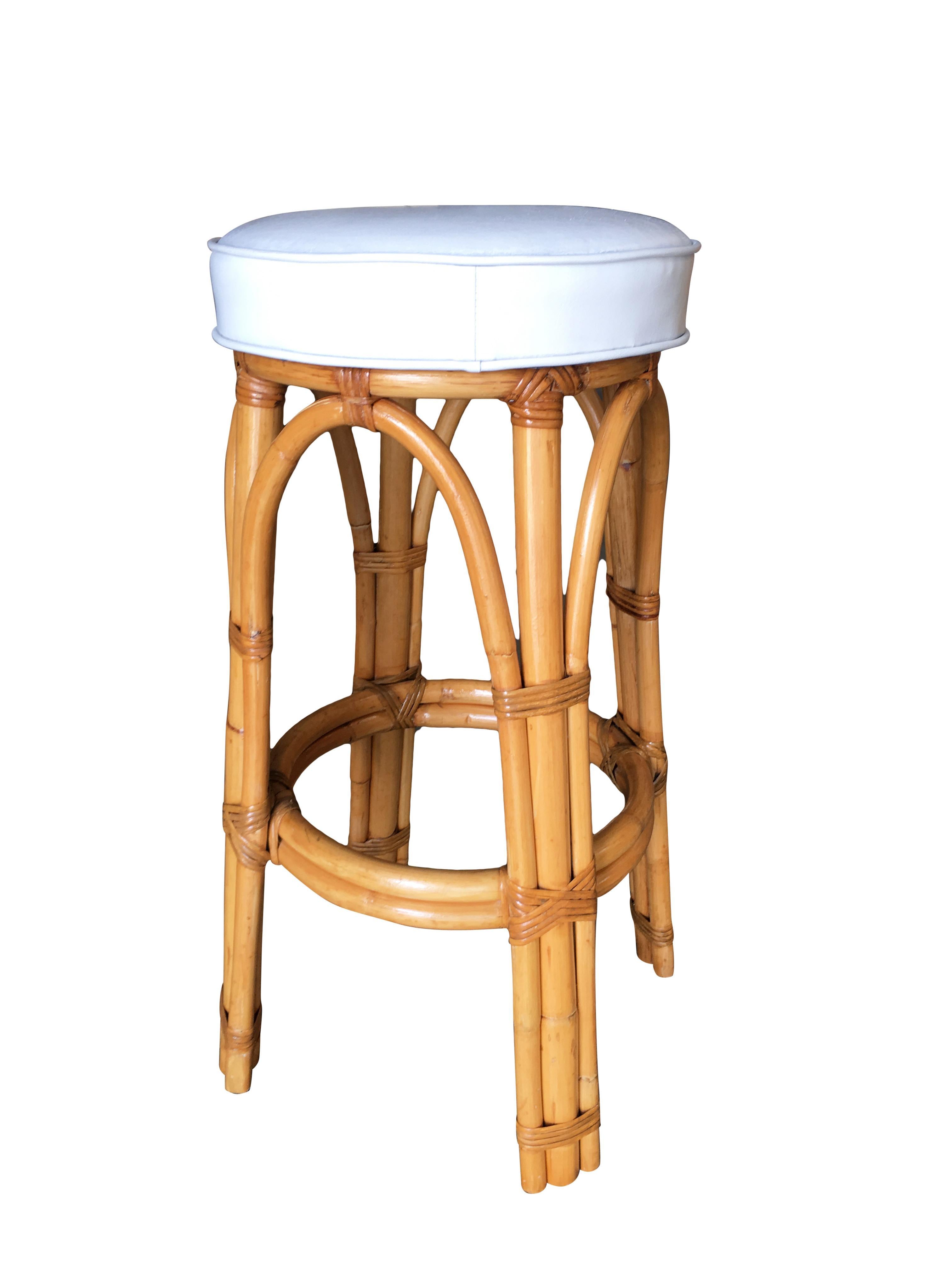 Set of three 1950s pole leg Rattan bar stool with white vinyl upholstery.

Custom cushions C.O.M. (Costumers Own Material) are included in the price. Simply supply the fabric and we have the cushions made for you. If you need help sourcing fabric we