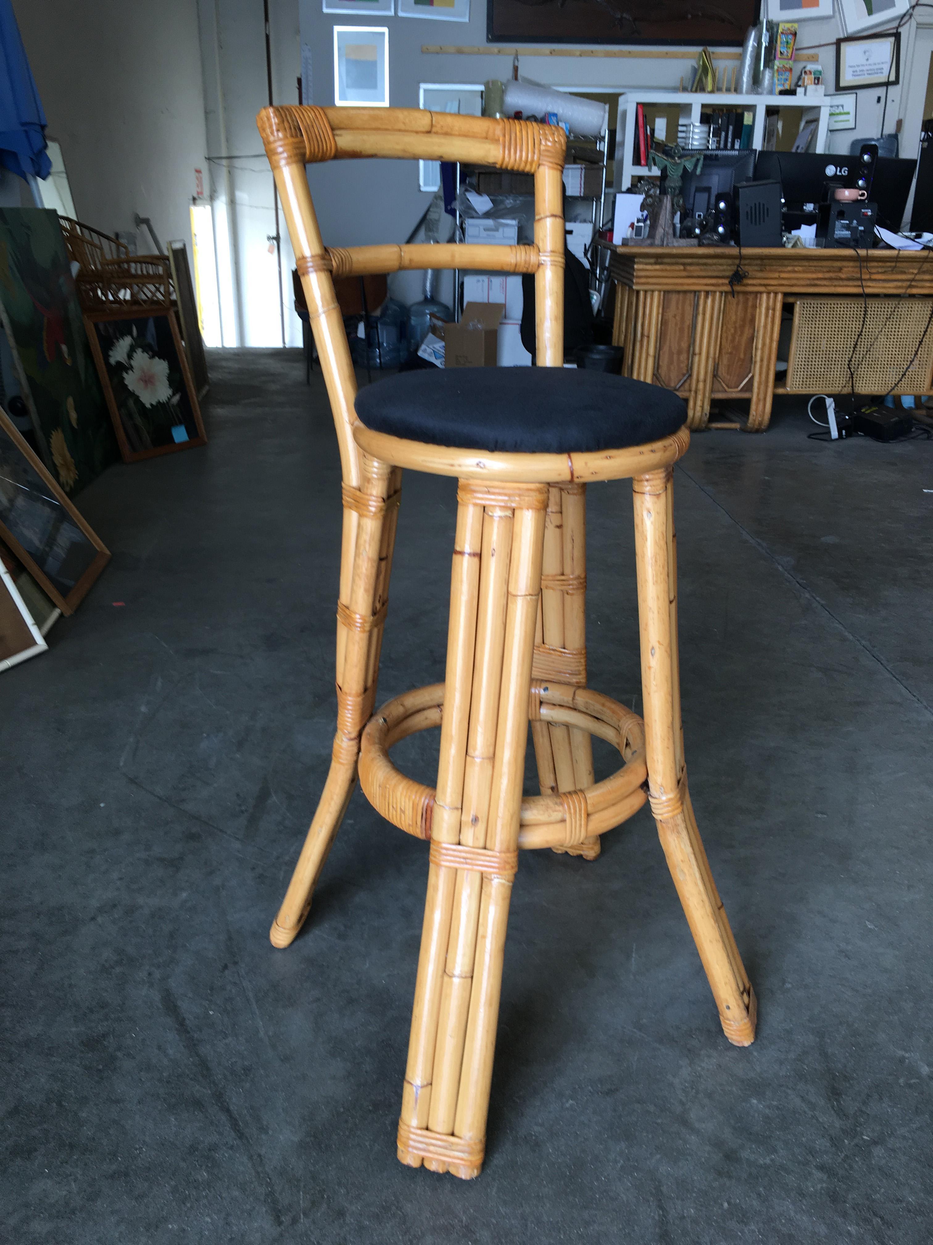 Set of two rattan bar stools with black cotton seats and three strand rattan pull legs. Each stool comes with a full formed backrest complimented by Branching 3 strand legs. All pieces listed are professionally restored. All our rattan, bamboo and