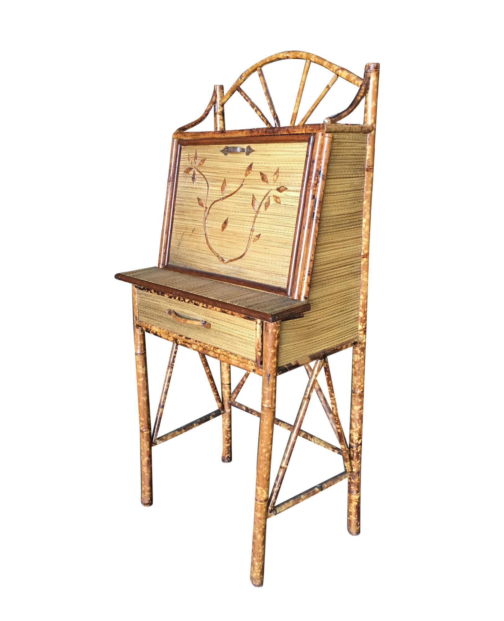 Tiger bamboo secretary desk with handwoven rice mat coverings and cut bamboo floral sculpture along the front, centre drawer and flip down front opening to five small selves for papers and stationary.

Restored to new for you.

All rattan,