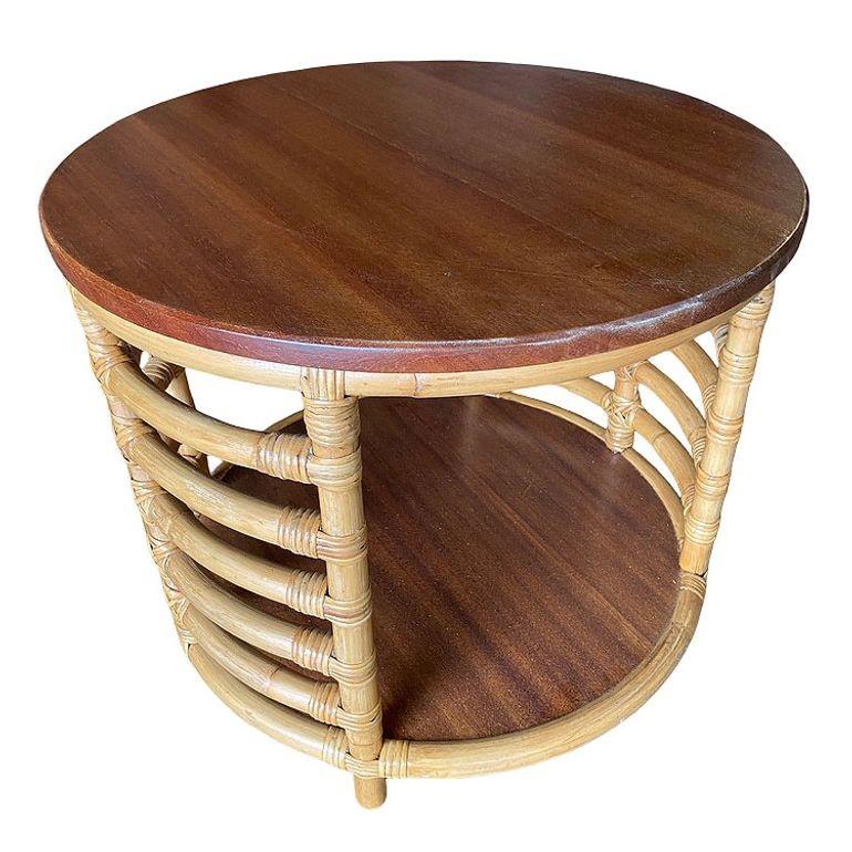 This beautifully restored Postwar two-tier round rattan coffee table with twin mahogany tops and wrapped stick rattan ladder sides. It blends style and vintage charm with modern comfort. All meticulously refinished to highlight the natural rattan’s