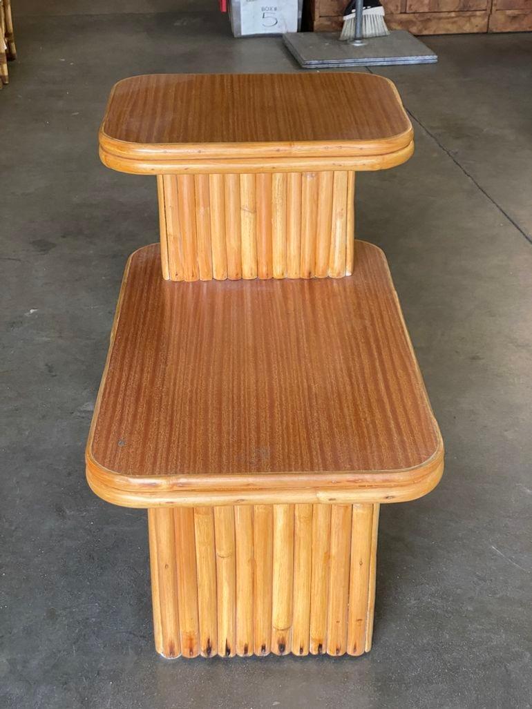 This beautifully restored Paul Frankl-inspired rattan blends vintage charm with modern comfort. The two-tiered side table features vertically stacked rattan bases with Formica tops in the style of Paul Frankl. Meticulously refinished to highlight
