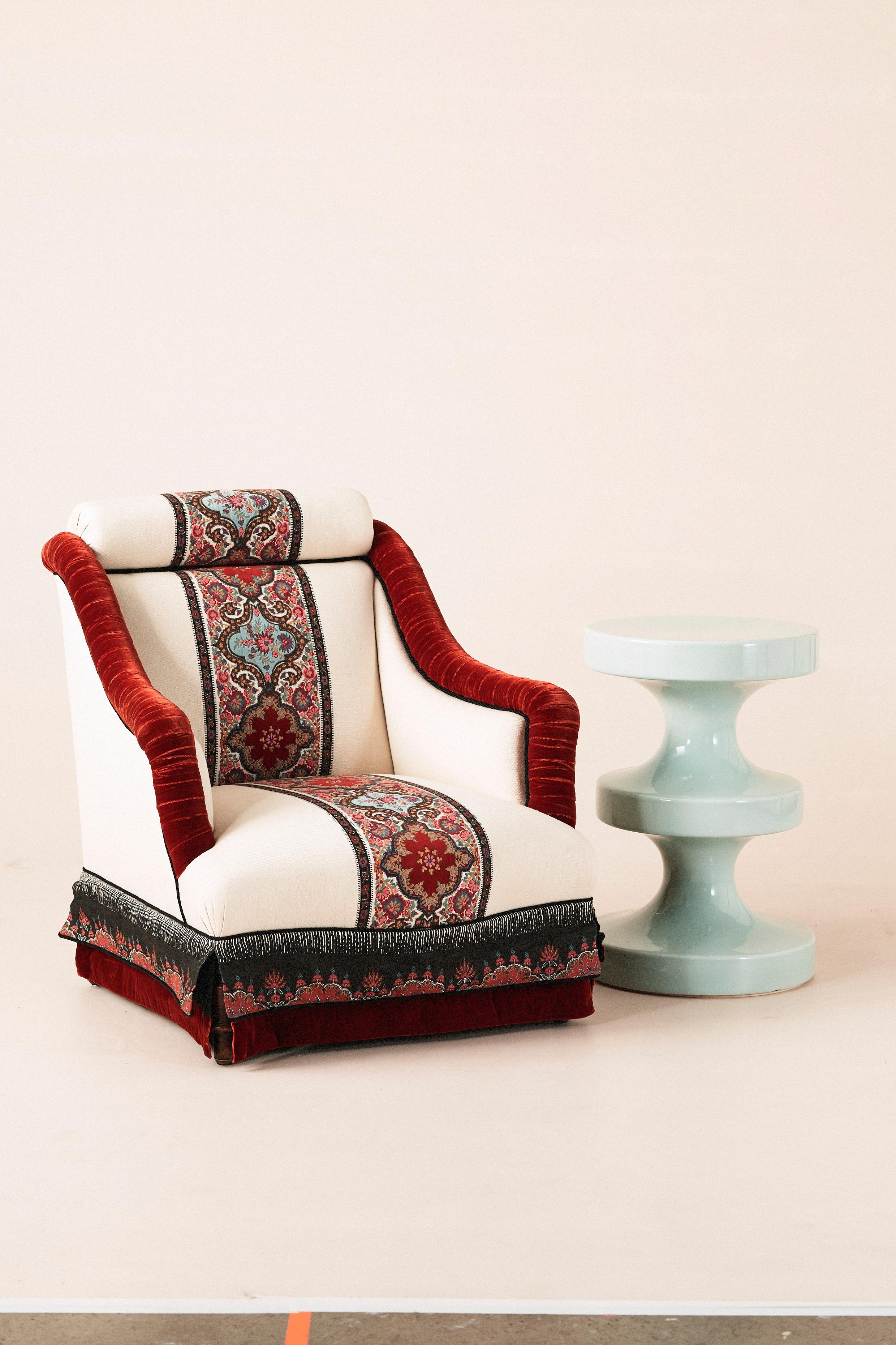 Fauteuil vintage du d�ébut du 20ème siècle avec une solide structure en bois sculpté, récemment restauré dans un luxueux tissu Pierre Frey. Le fauteuil combine un riche velours rouge le long des accoudoirs et de la base avec des panneaux brodés de