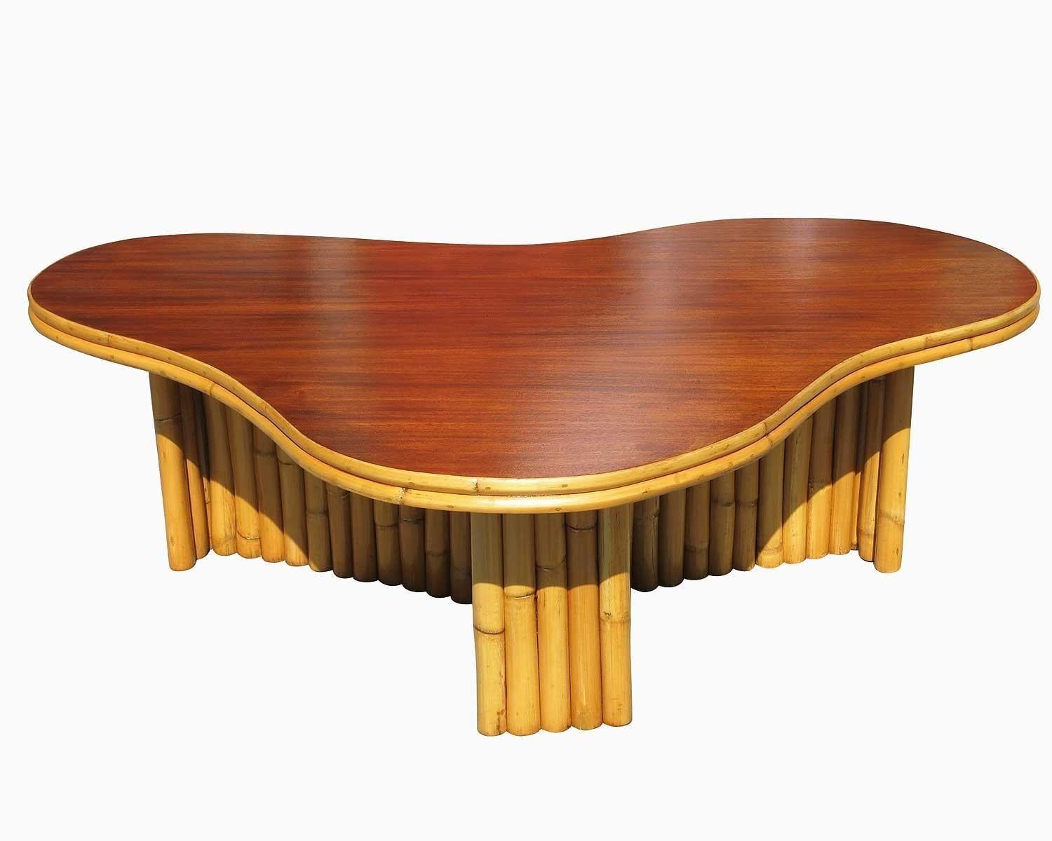 This beautifully restored rattan table blends style and vintage charm with modern comfort. Made in 1950, this biomorphic rattan coffee table with an amoeba-shaped mahogany top, circa 1950. This table features a grouped pole leg design and stick