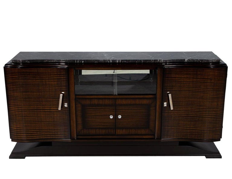 Restored Vintage French Art Deco marble top sideboard bar cabinet. This Art Deco bar cabinet hails from 1940’s France. The piece is topped with a black marble top and sits atop a black pedestal base. There are two curved doors at each end housing