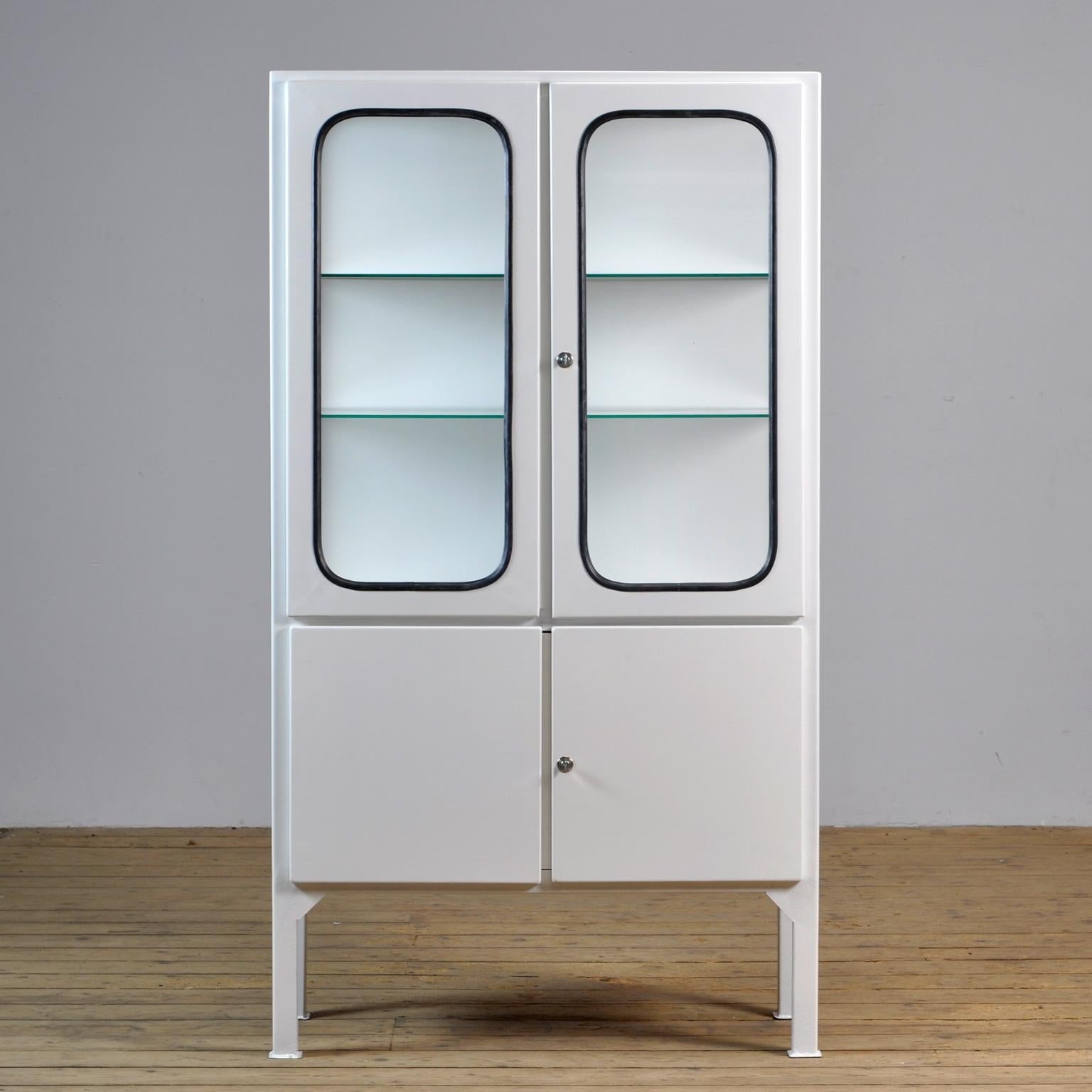 This medicine cabinet was designed in the 1970s and was produced circa 1975 in Hungary. It is made from iron and antique glass, and the glass is held by a black rubber strip. The cabinet features two adjustable glass shelves and functioning