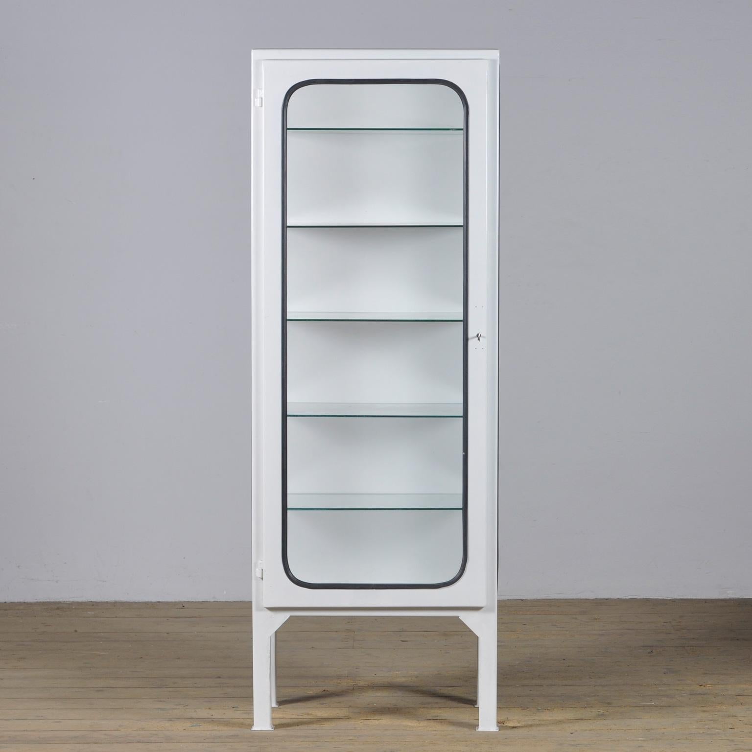 This medical cabinet was designed in the 1970s and was produced circa 1975 in hungary. It is made from iron and glass with new glass shelves. The glass is held by a black rubber strip. The cabinet features five adjustable glass shelves and a