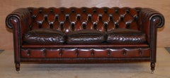 Divano club Chesterfield restaurato in pelle bordeaux color sangue di bue su gambe tornite