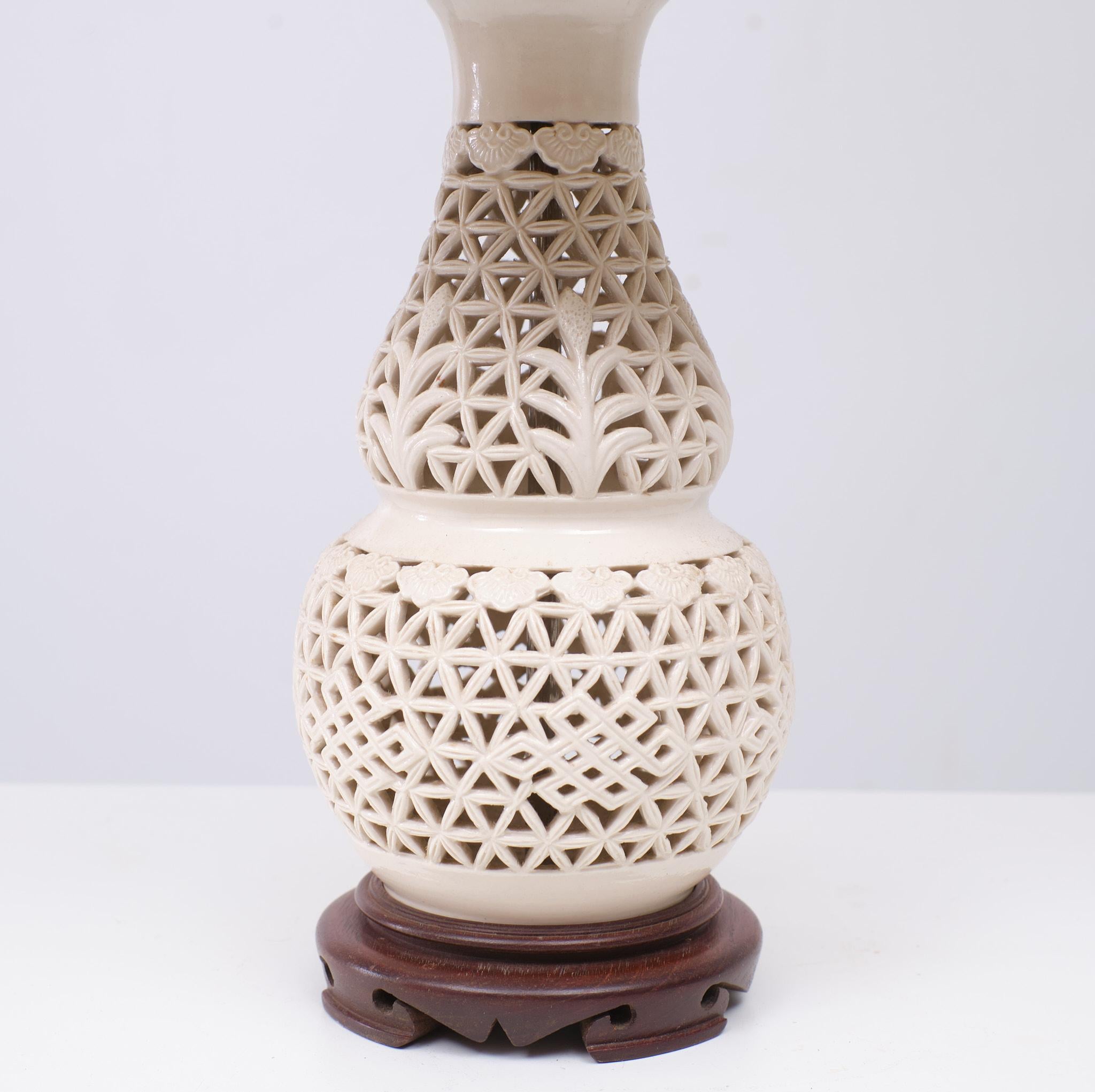 Blanc De Chine lamp in perfect, working condition. Openwork gloss off white ceramic 20th century, pierced porcelain vase form, brass mounts, on a wood base. Shades included. Clean and striking the off white ceramic displays an interesting open work