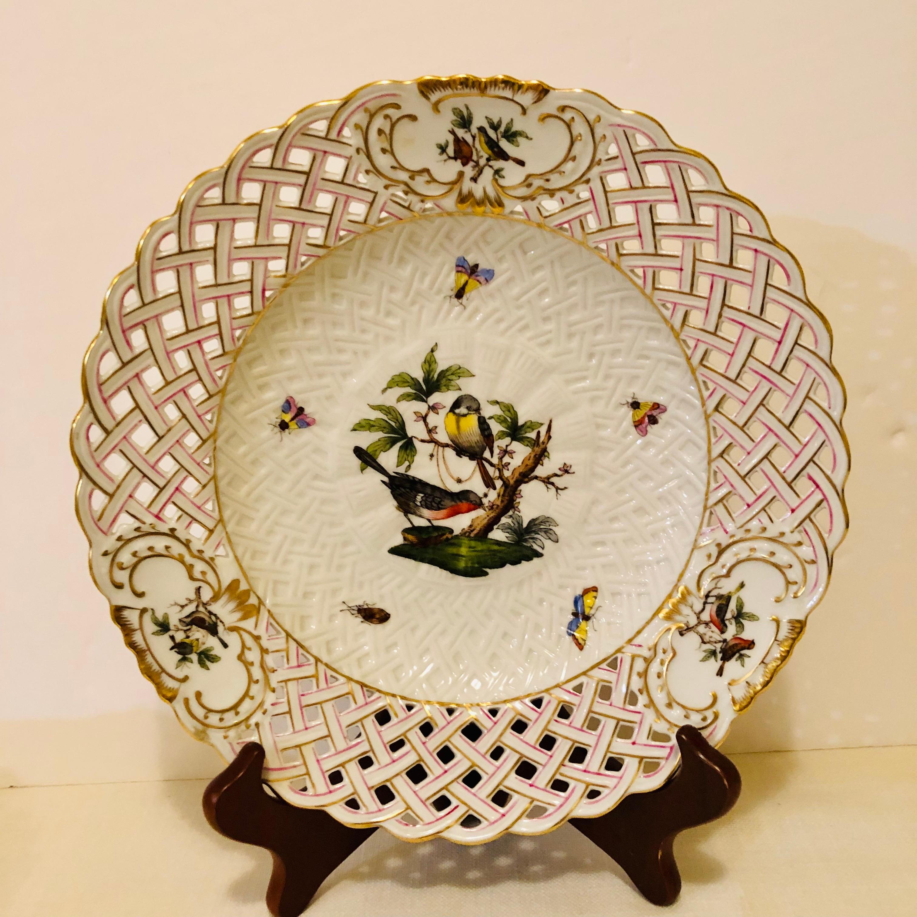 This is a stunning Herend Rothschild bird reticulated plate that has a central painting of two birds surrounded by a pink and gold reticulated border and three cartouches with different paintings of birds. The paintings of birds have painted accents