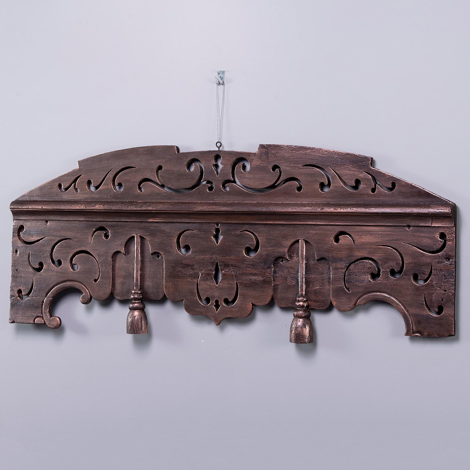 Carved wood over-mantel (fireplace) piece is just under 50” long with arched top and two carved tassels. Metallic bronze color painted finish, circa 1910. Unknown maker. Found in Belgium. Three available. Sold and priced individually.