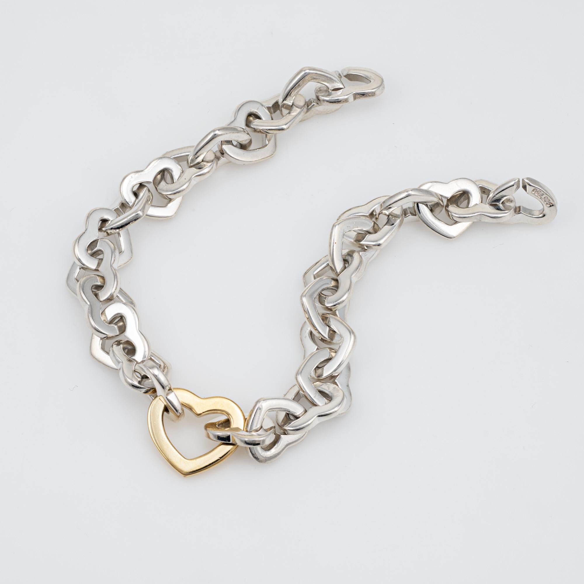 Stylish and finely detailed vintage Tiffany & Co heart link bracelet, crafted in sterling silver & 18 karat yellow gold.  

The bracelet features interlocking heart shaped links in sterling silver, with a larger 18k yellow gold heart link to the