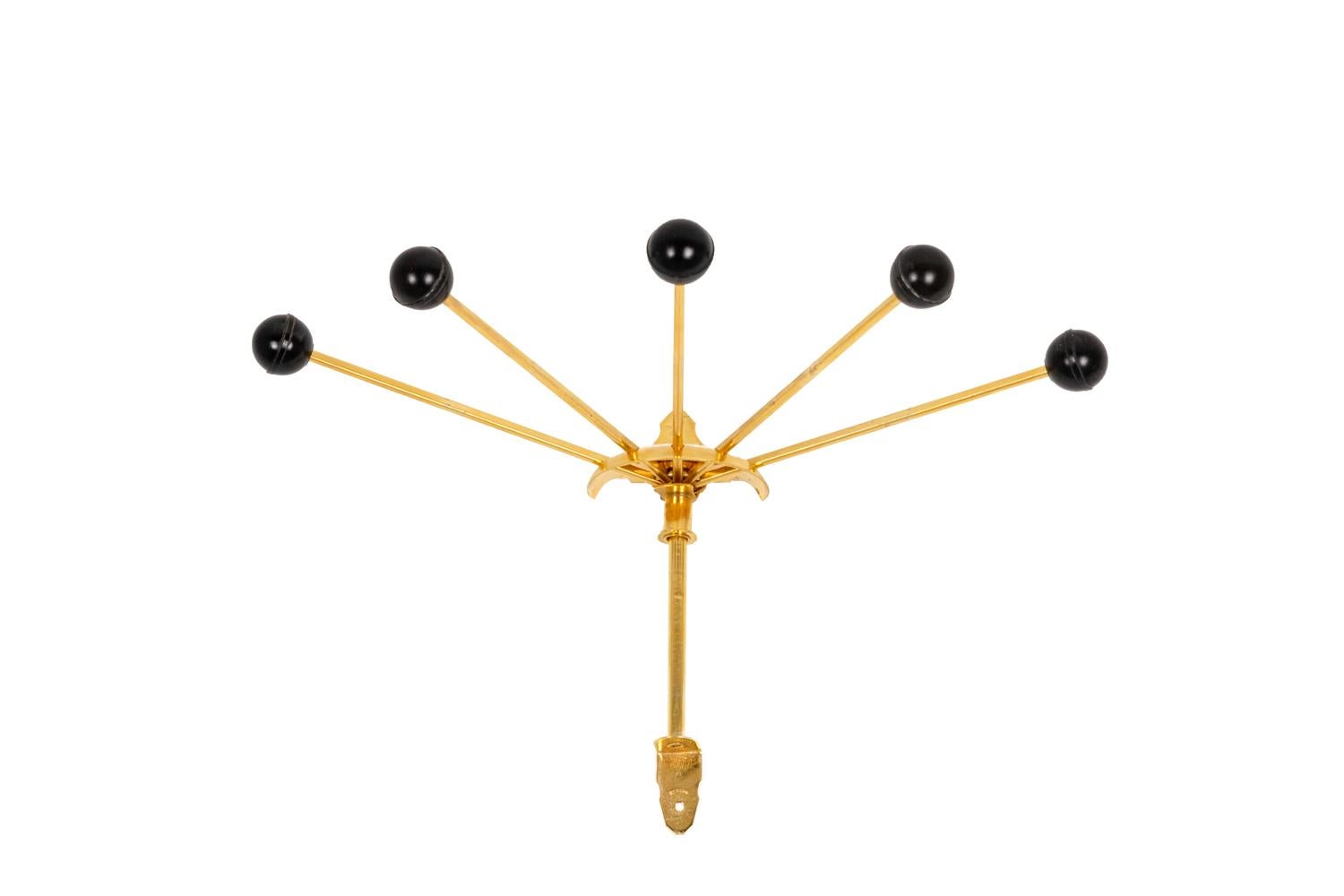 Wall bracket retractable coat-hanger, with five branches in gilt brass with black Lucite round ends.

Work realized in the 1950s.

Dimensions: closed H 30 x D 13 cm, opened H 25 x D 25 cm.