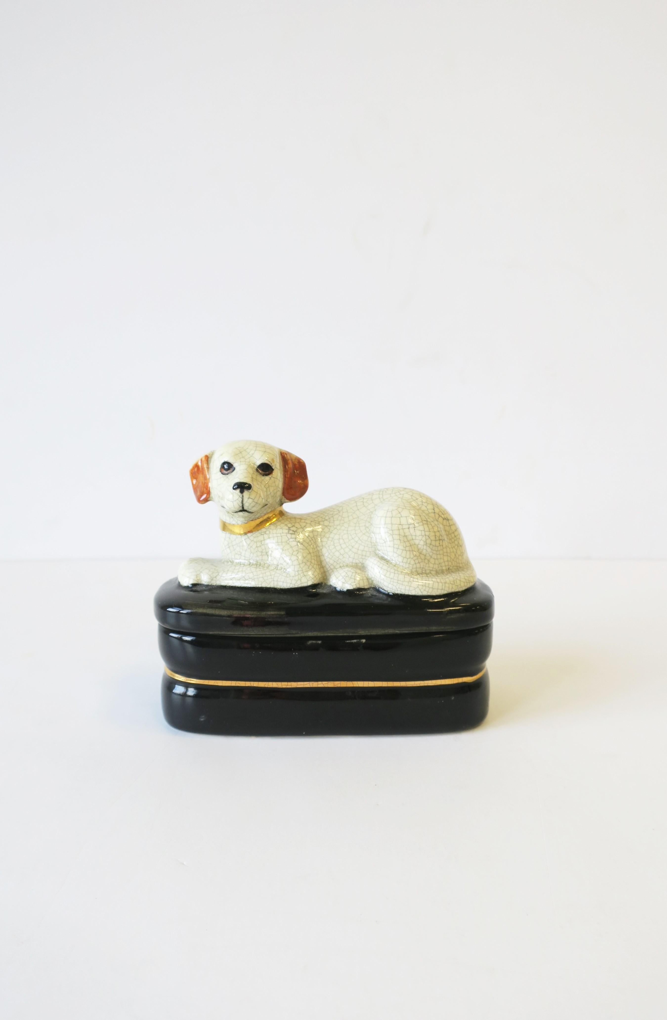 A ceramic retriever dog on pillow decorative box. Great as a standalone piece or to hold small trinket items or jewelry. Colors include: Off-white, black, gold, and touches of brown on ears. A great piece for a console, desk, vanity, nightstand