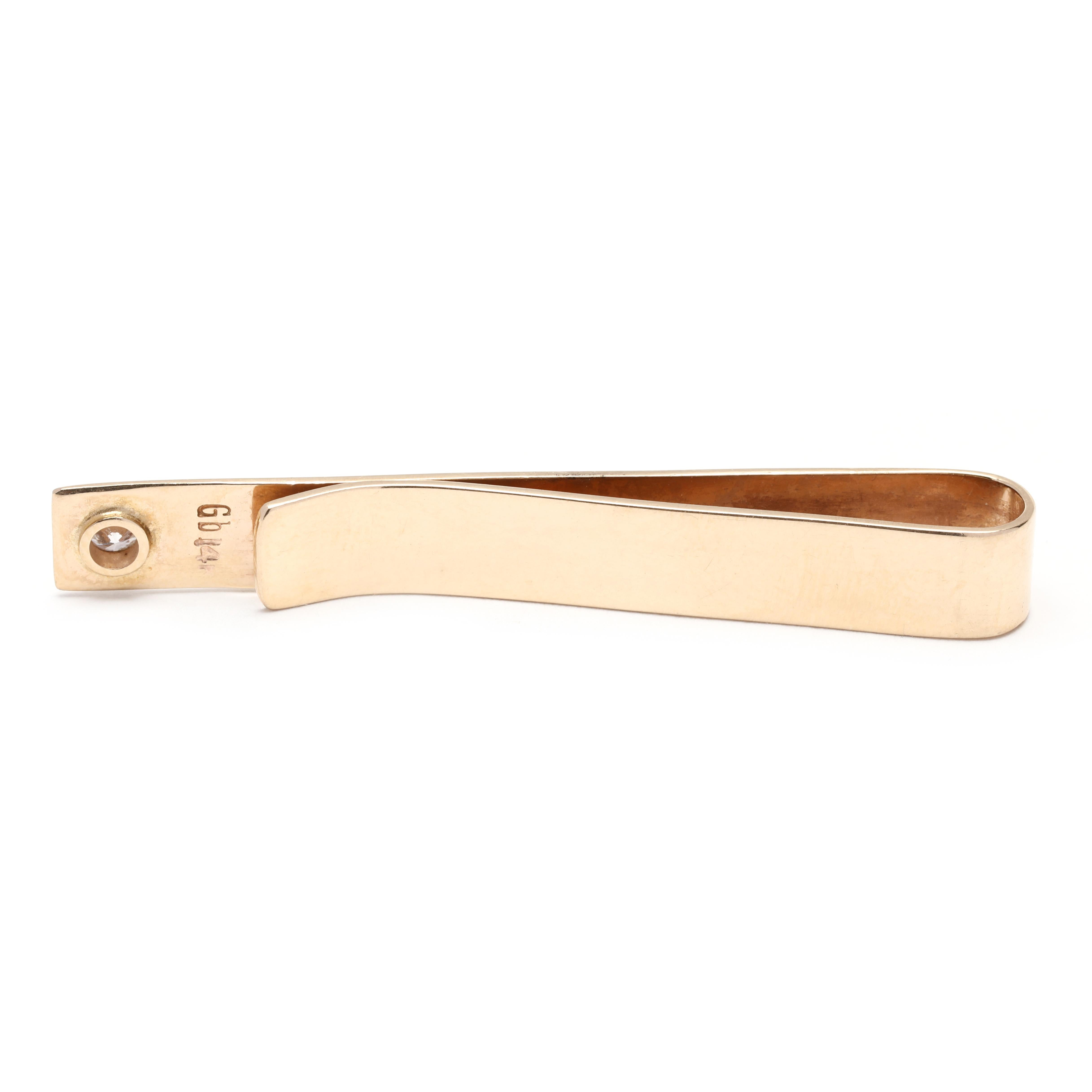 This retro-inspired diamond tie bar is a stylish and sophisticated accessory for any gentleman. Crafted in 14K yellow gold, it features a simple design with a sparkling 0.14ct diamond at the center. The length of the tie clip is 1 7/8 inches, making