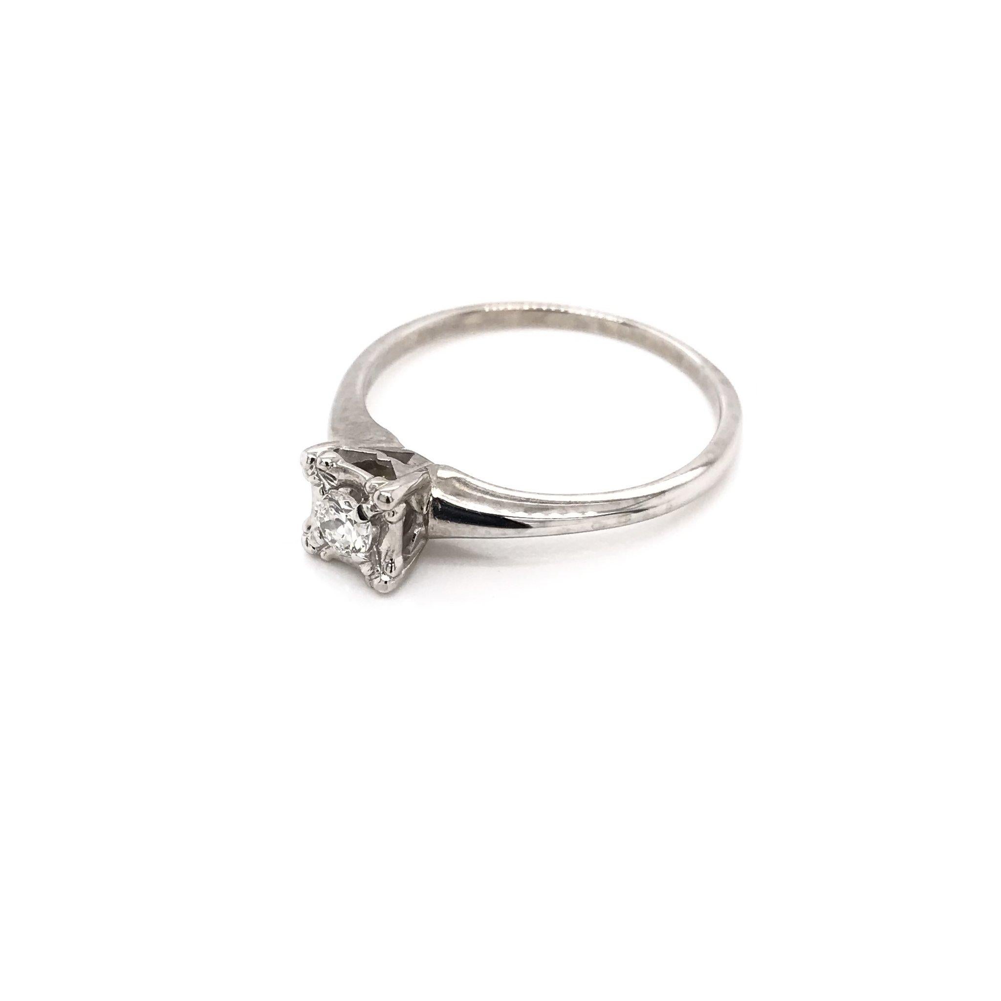 This sweet Mid Century diamond ring was crafted sometime during the Retro design period ( 1940-1960 ). The 14k white gold setting features a simple diamond solitaire style. The center diamond measures approximately 0.17 carats and grades I in color,