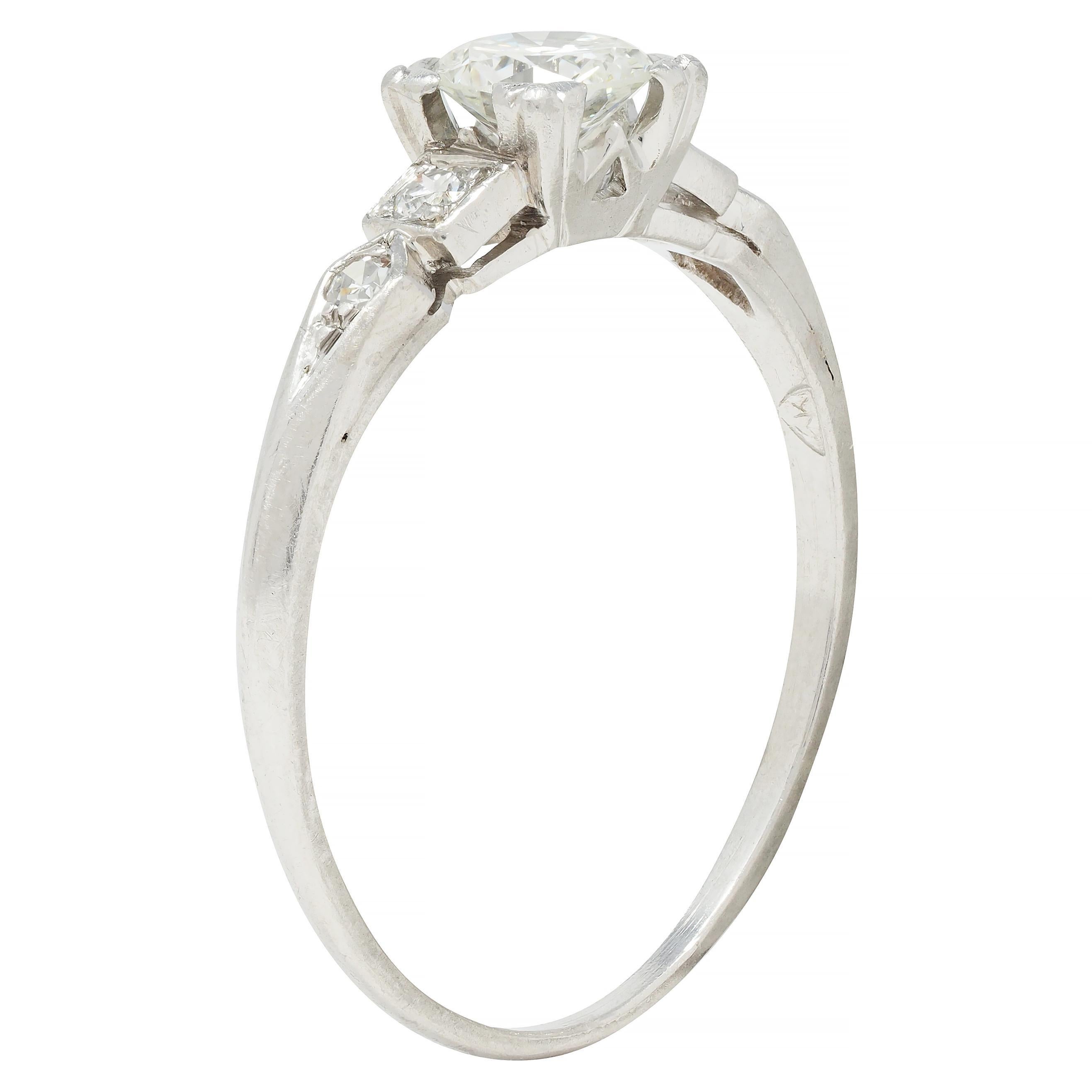 Centering a transitional cut diamond weighing approximately 0.41 carat total - I color with VS2 clarity
Set with tri-split prongs in a square form basket with a pierced 'W' motif profile 
Flanked by cathedral shoulders bead set with single cut