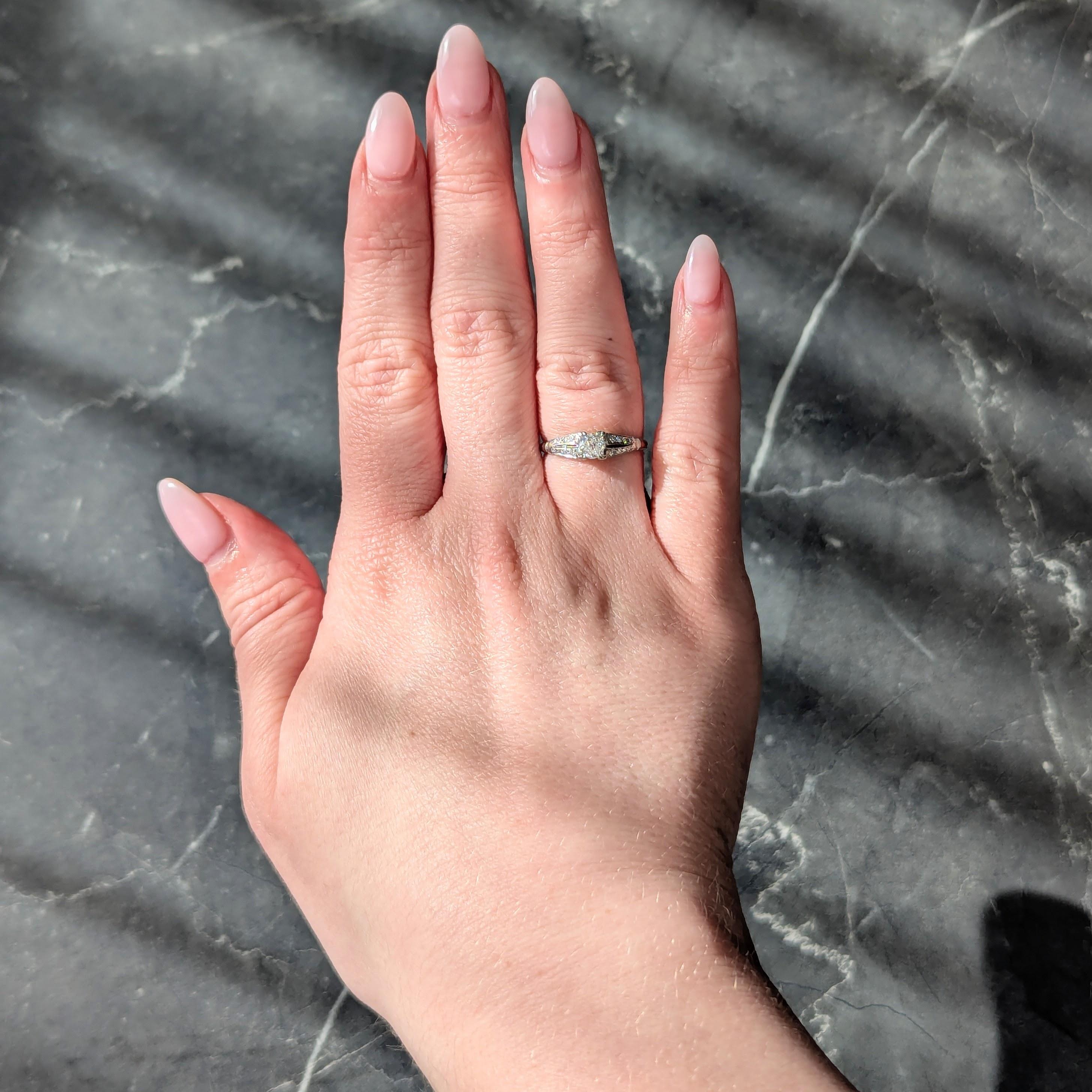 Al centro un diamante vecchio taglio europeo del peso di circa 0,35 carati - colore I con purezza VS2
Incastonato con rebbi tripartiti in una testa di forma quadrata e affiancato da spalle cattedrali.
Perline incastonate con file di diamanti a