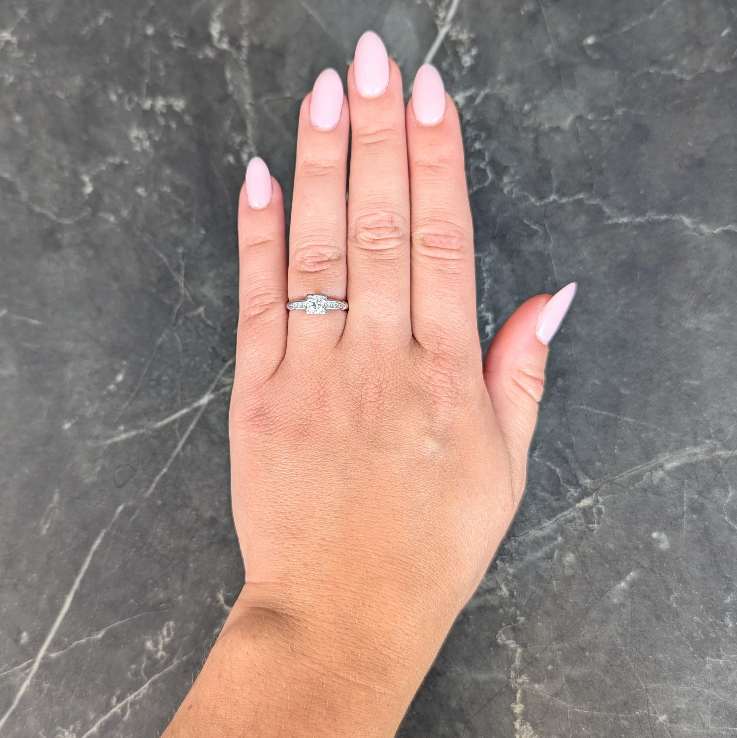 Centering a round brilliant cut diamond weighing approximately 0.51 carat - H color with VS clarity
Set by tri-bead prongs in a stylized square form head 
Flanked by cinched cathedral shoulders
Channel set with single cut diamonds 
weighing