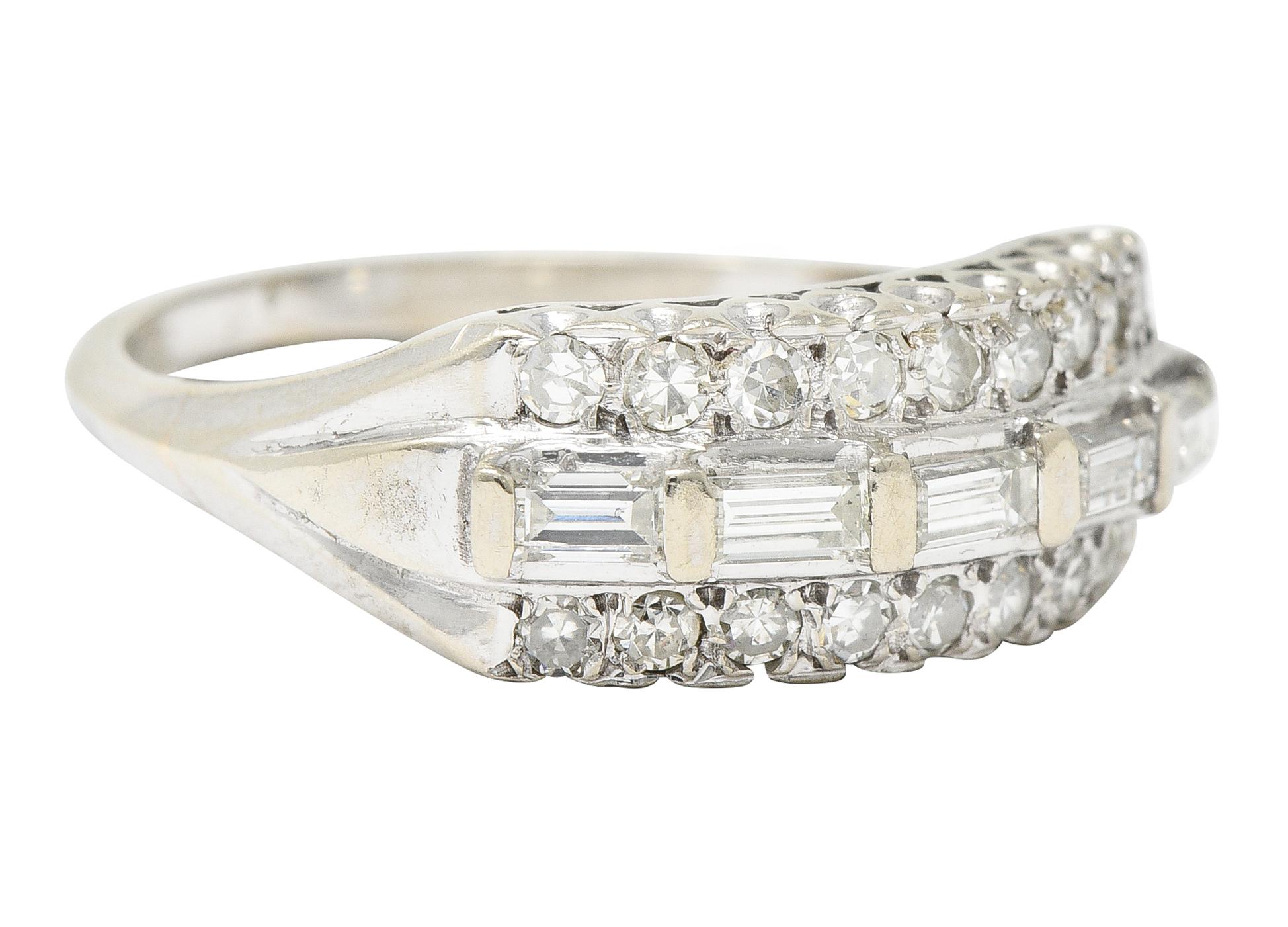 Band ring is comprised of three tiered rows of diamonds with a fishtail profile.Centering bar set baguette cut diamonds flanked North to South by single cut diamonds. Total diamond weight is approximately 0.65 carat - H/I with SI to VS clarity.