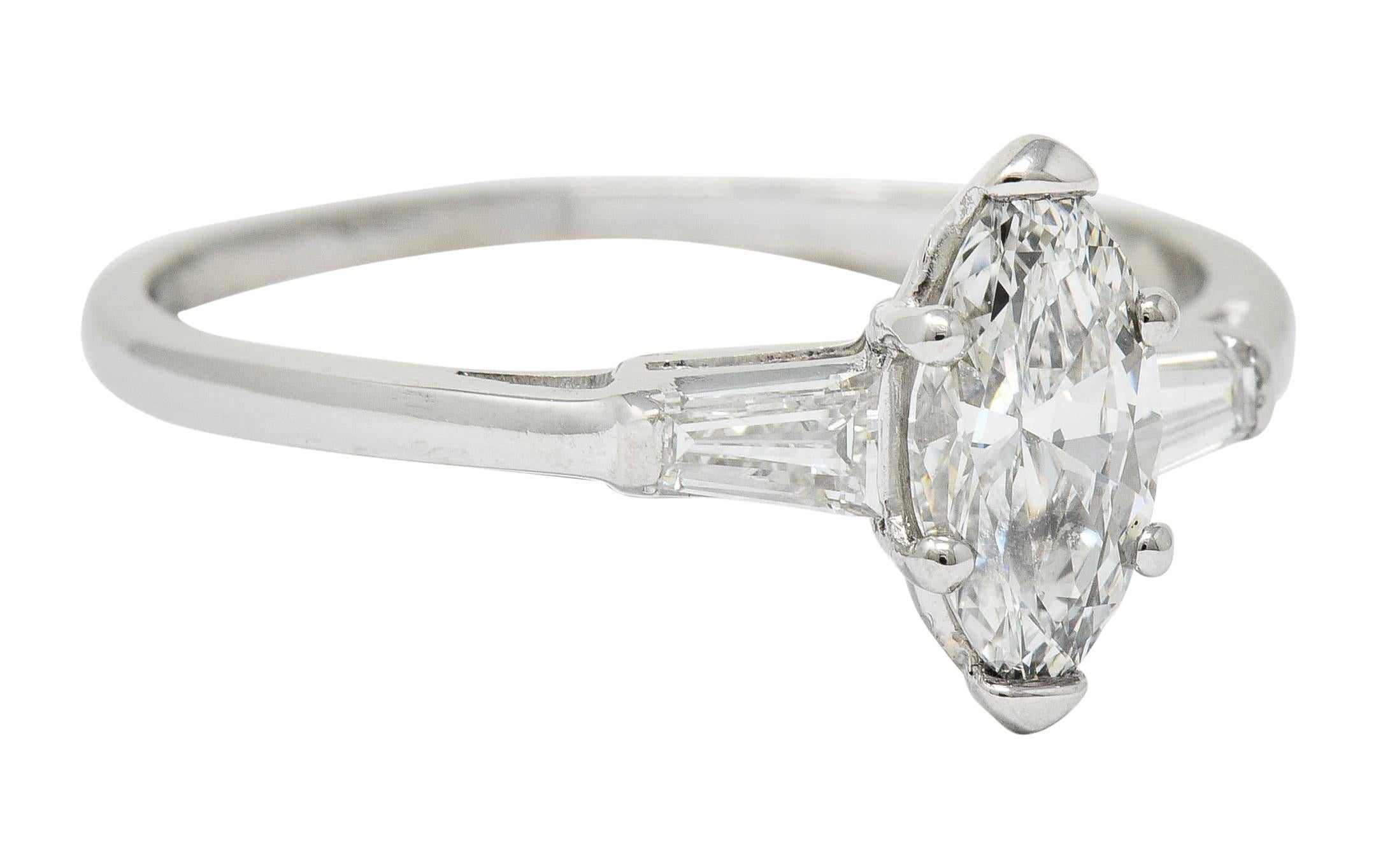 Centering a marquise cut diamond weighing 0.85 carat; I color with VS1 clarity

Flanked by two tapered baguette cut diamonds weighing in total approximately 0.25 carat; well-matched to center

Stamped for platinum

Circa: 1950s

Ring Size: 9 &