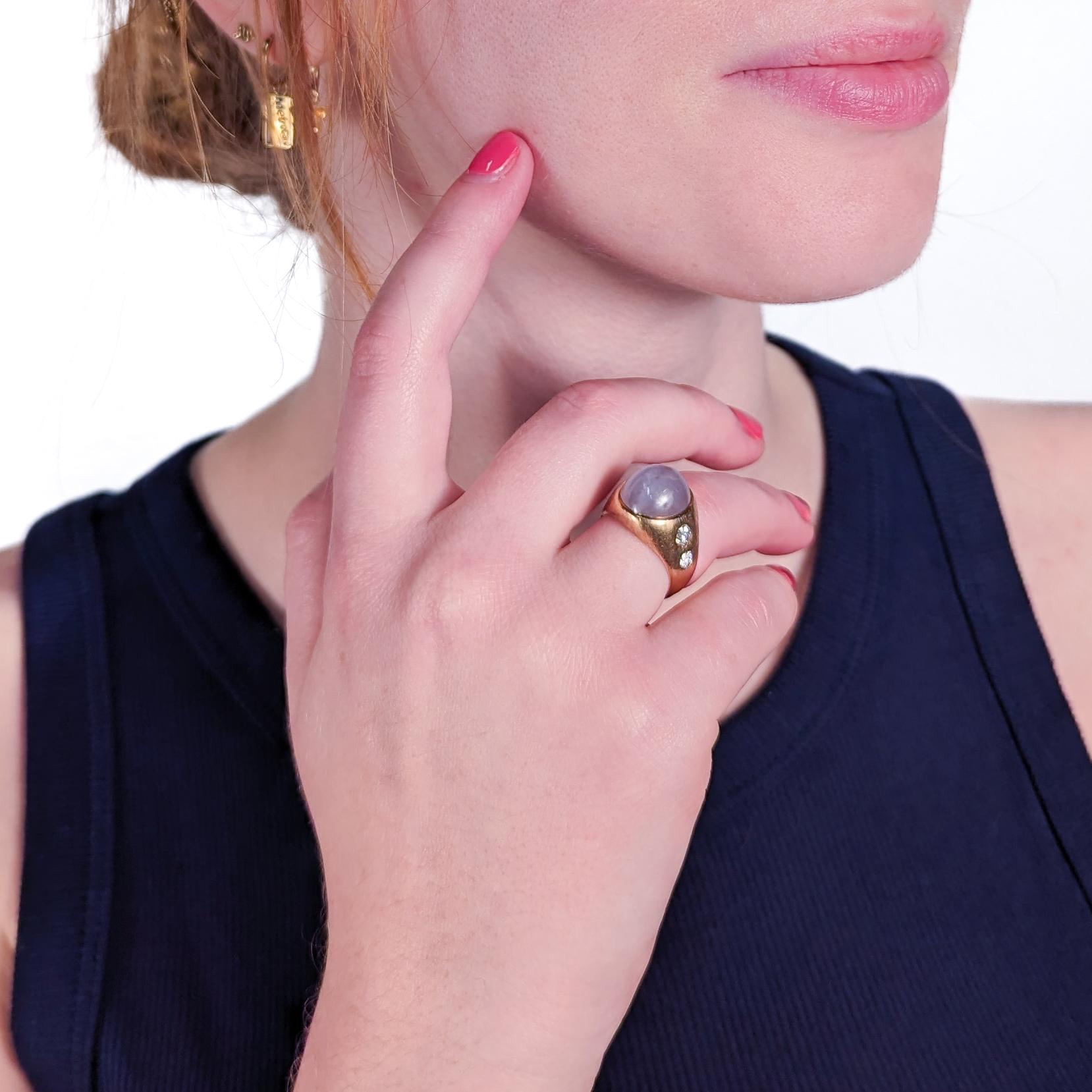 A very fine Retro star sapphire and diamond gypsy ring.

In 14k gold. 

Center set with a ca. 14.75 carat smooth oval star sapphire cabochon that is flanked by 4 round Old European cut flush set diamonds in the sides of the band.

Accompanied by a