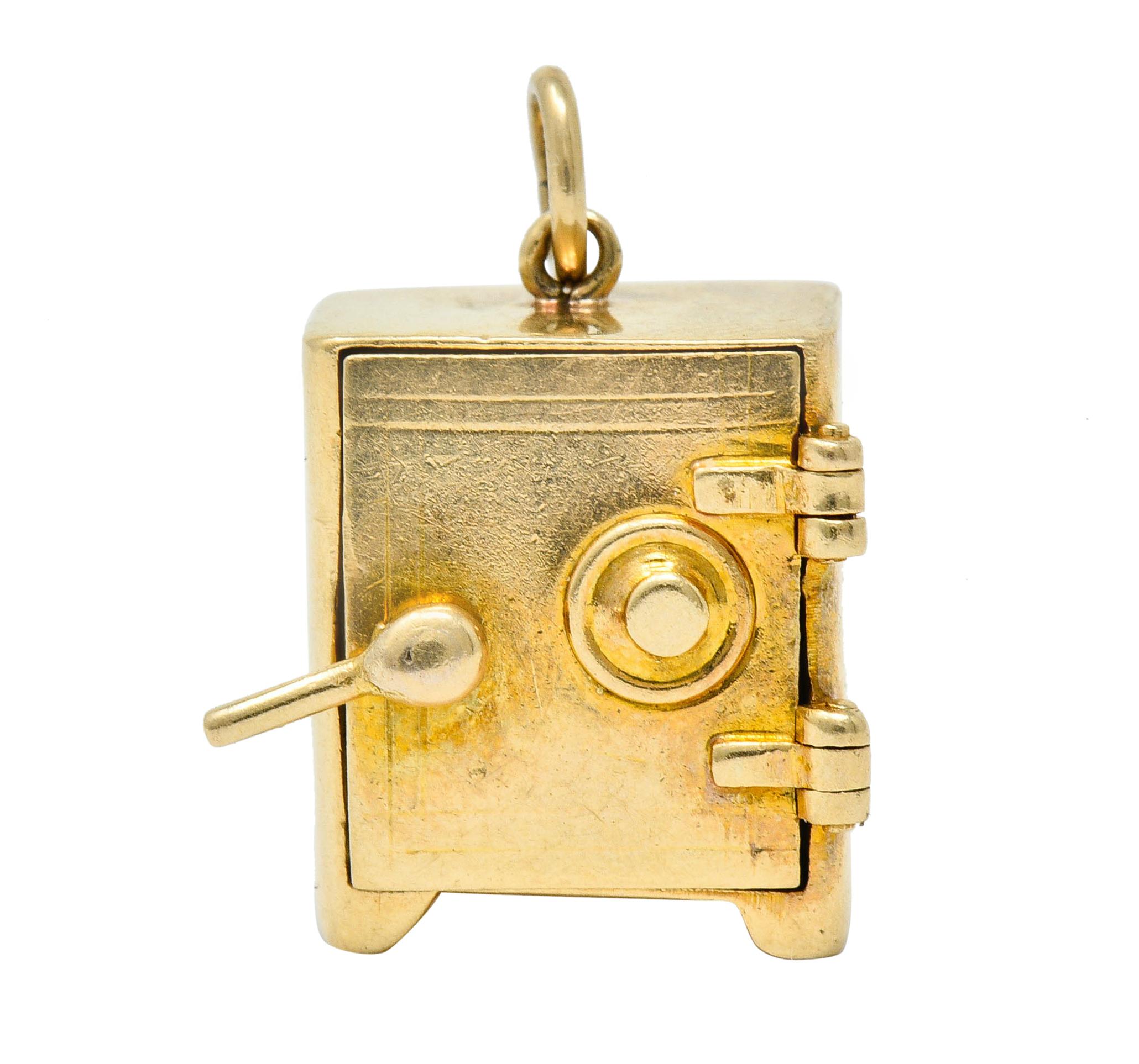 Designed as a safe with a functioning handle that pivots to unlock door

Door opens on a hinge to reveal a compactly folded dollar bill

Completed by a jump ring bale

Stamped 14K for 14 karat gold

Measures: 7/16 x 3/4 inch (including bale)

Total
