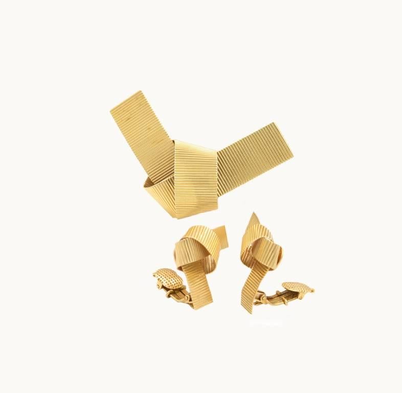 A vintage retro bow style set in 14 karat yellow gold with ribbed gold design from circa 1950.  This set includes a matching bow brooch and clip-on earring set.

Brooch measures approximately 2.36 inches in length and 1.45 inches in width.  The