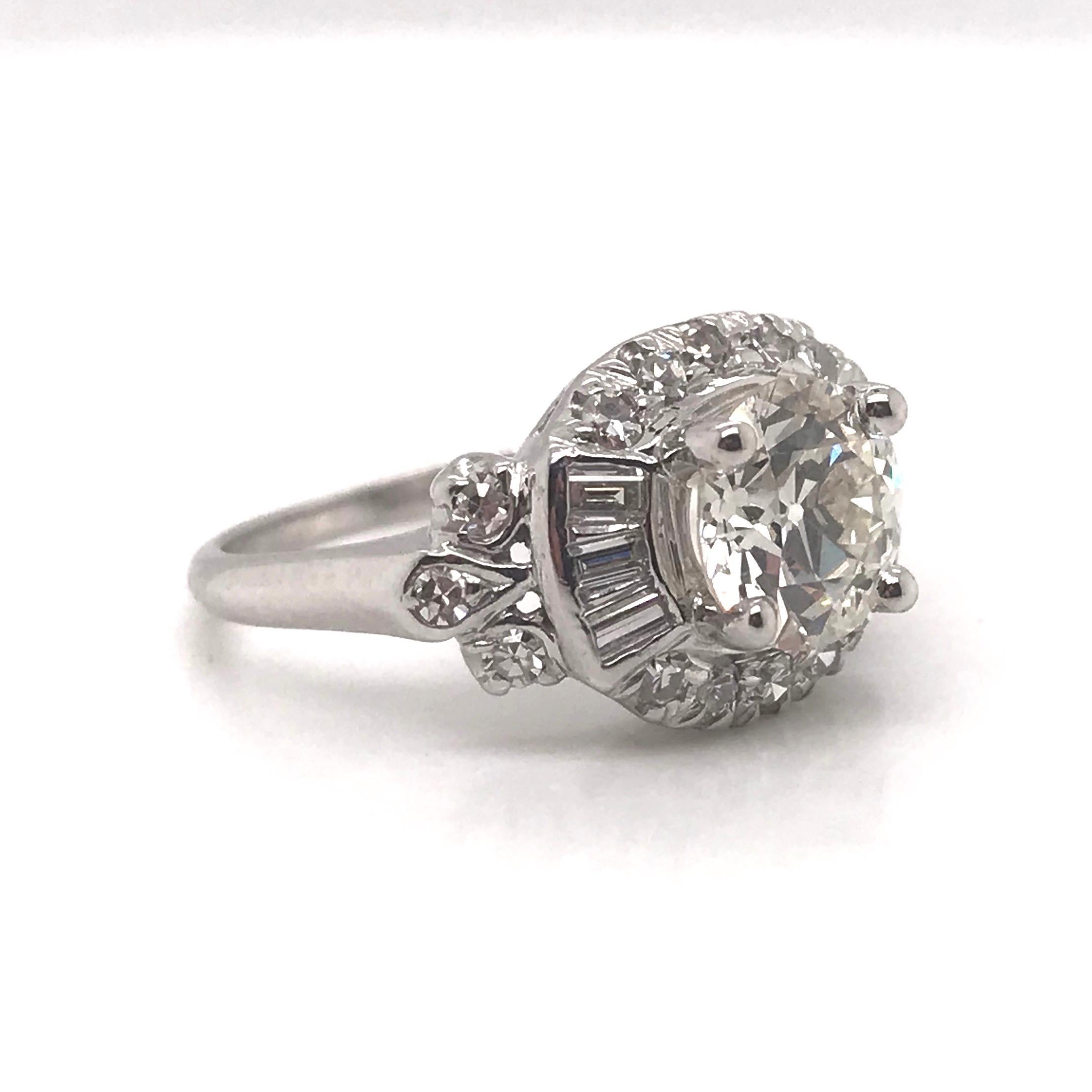 This beautiful ring was crafted sometime during the Retro Era, (1940 - 1960).  The setting is 14K white gold accented by 16 smaller round cut diamonds & 6 baguette shaped diamonds. The center GIA certified diamond is a gorgeous 1.41 Carat OLD