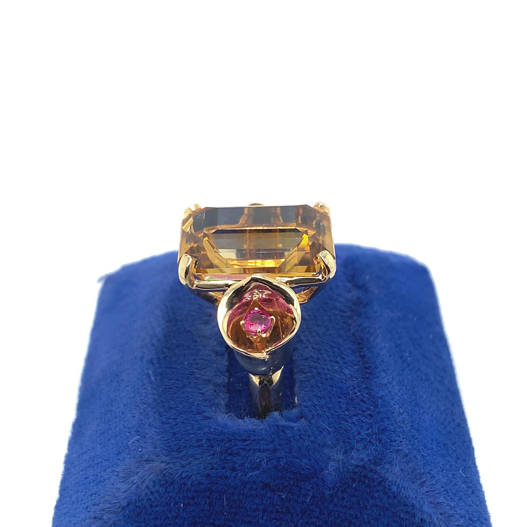 14K rosy yellow gold Retro ring featuring a large emerald cut citrine weighing 8.55 carats. The citrine measures about 15mm x 11mm and is accented by two round ruby accents measuring about 2.5mm, set in a tulip shaped flowers. The ring fits a size 5
