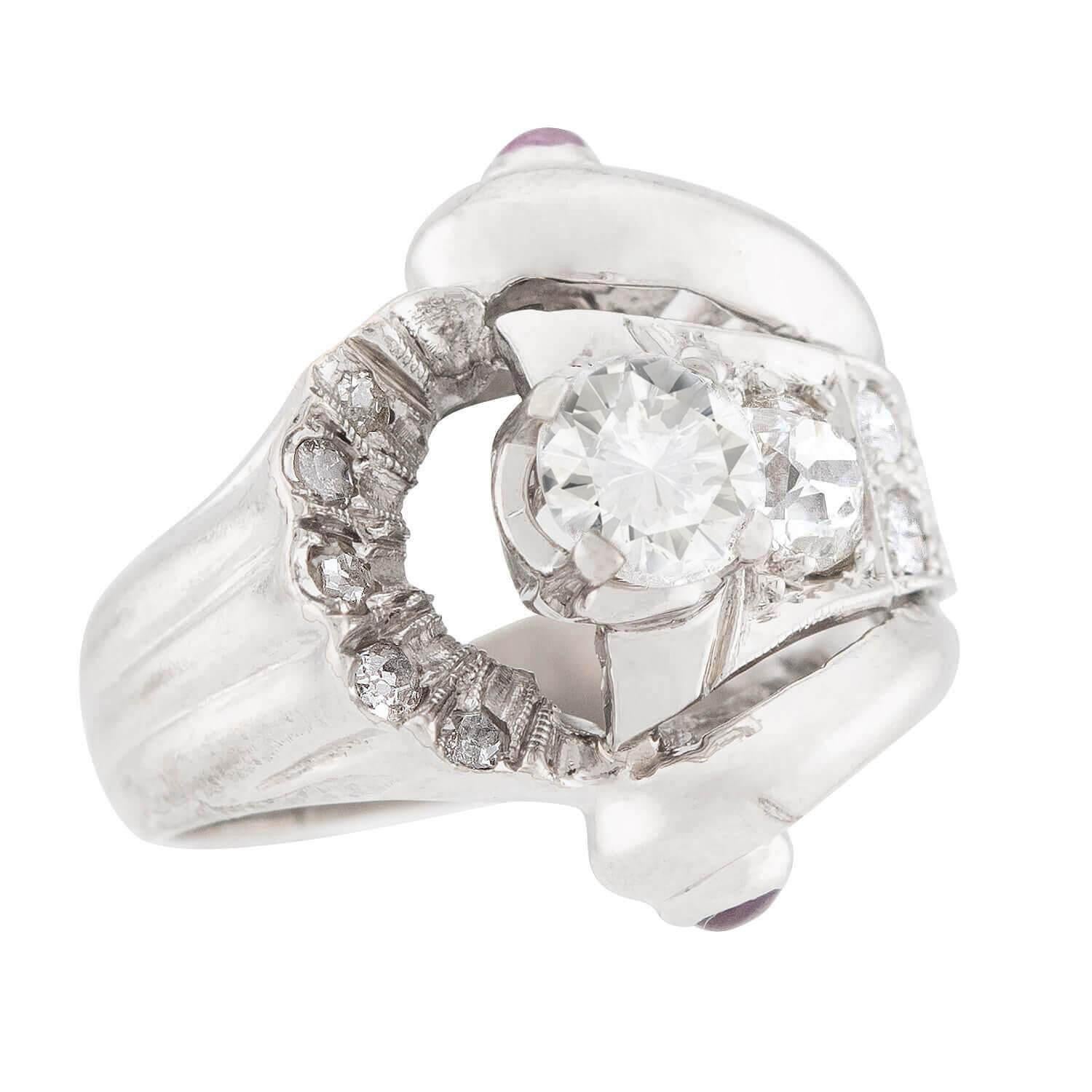 A fabulous diamond and sapphire ring from the Retro (ca1940s) era! Crafted in 14k white gold, this ring features a central 0.65ct modern round brilliant cut diamond held within a four-prong setting. The diamond is bordered on one side by a large