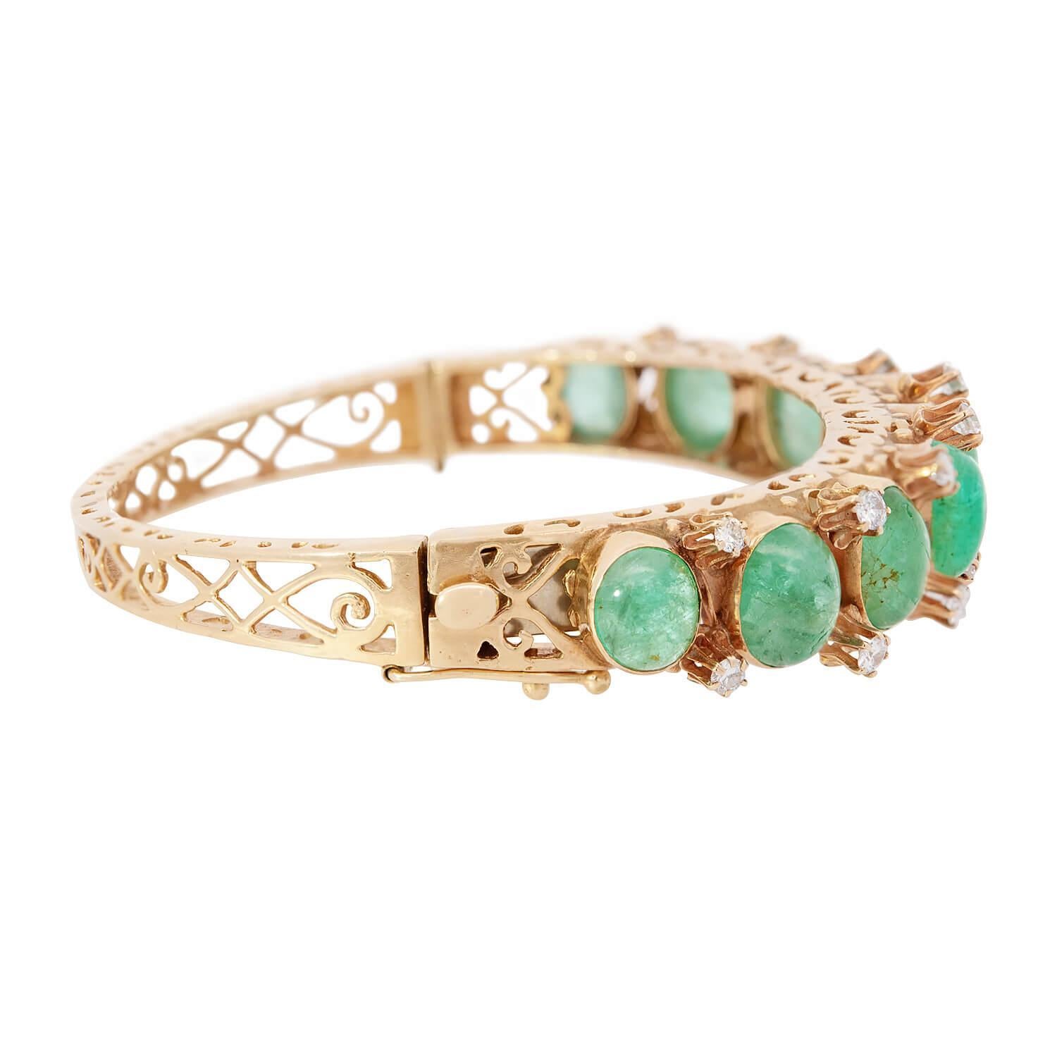 A gorgeous emerald and diamond bangle bracelet from the Retro (ca. 1960s) era! This fabulous bangle is crafted in 14k yellow gold, and features nine bezel-set emerald cabochons, which adorn the bracelet's surface. Overall, the rich green emerald